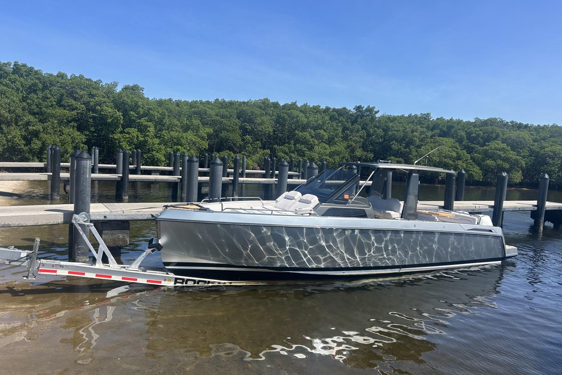 2023 Schaefer V33 boat docked at a marina with lush green trees.