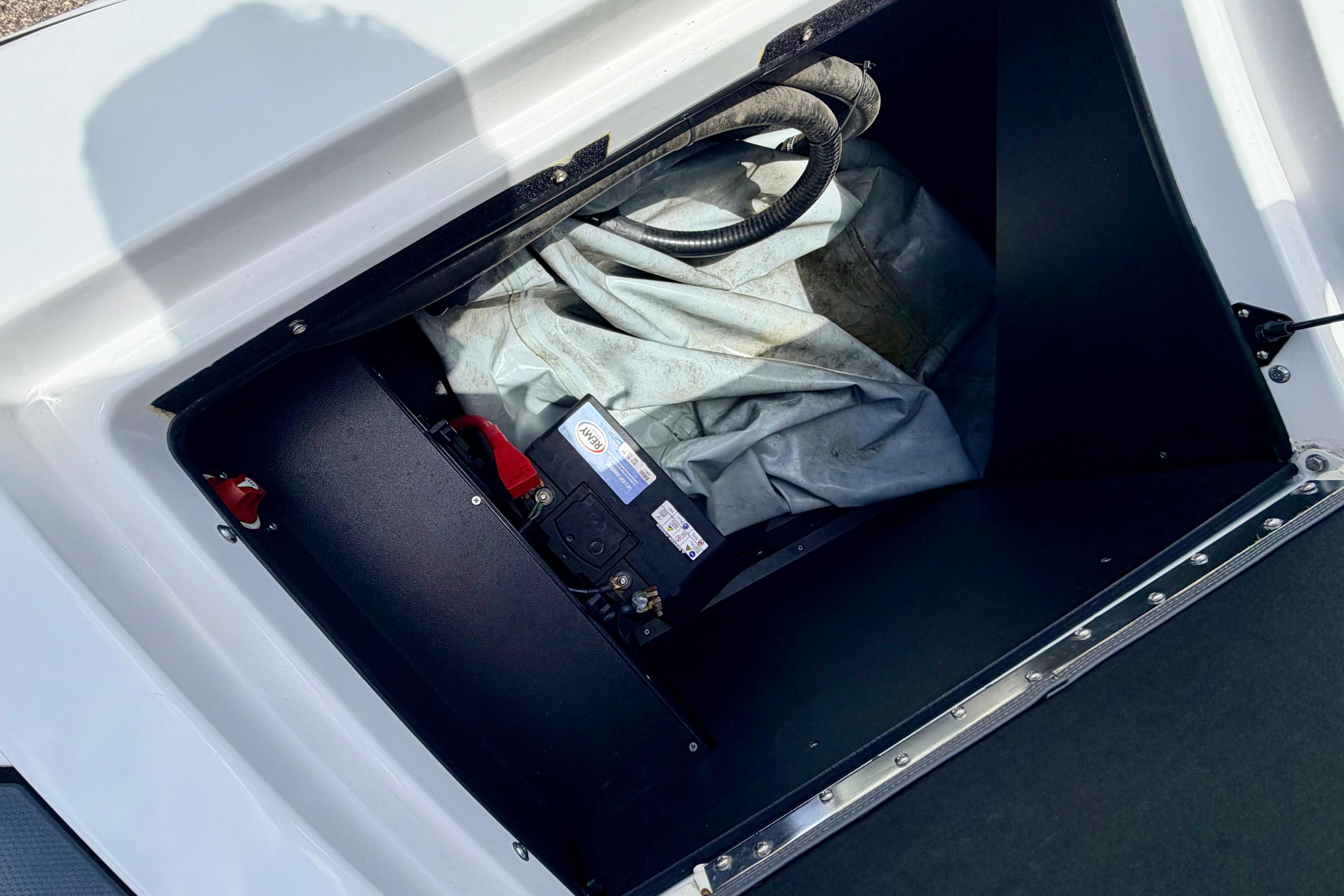 A storage compartment in the boat with a cover and battery compartment.