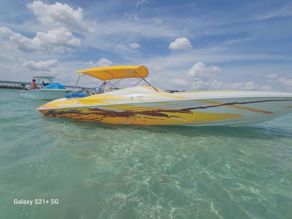 Sunsation 32 Dominator 2003 on clear water with yellow canopy.