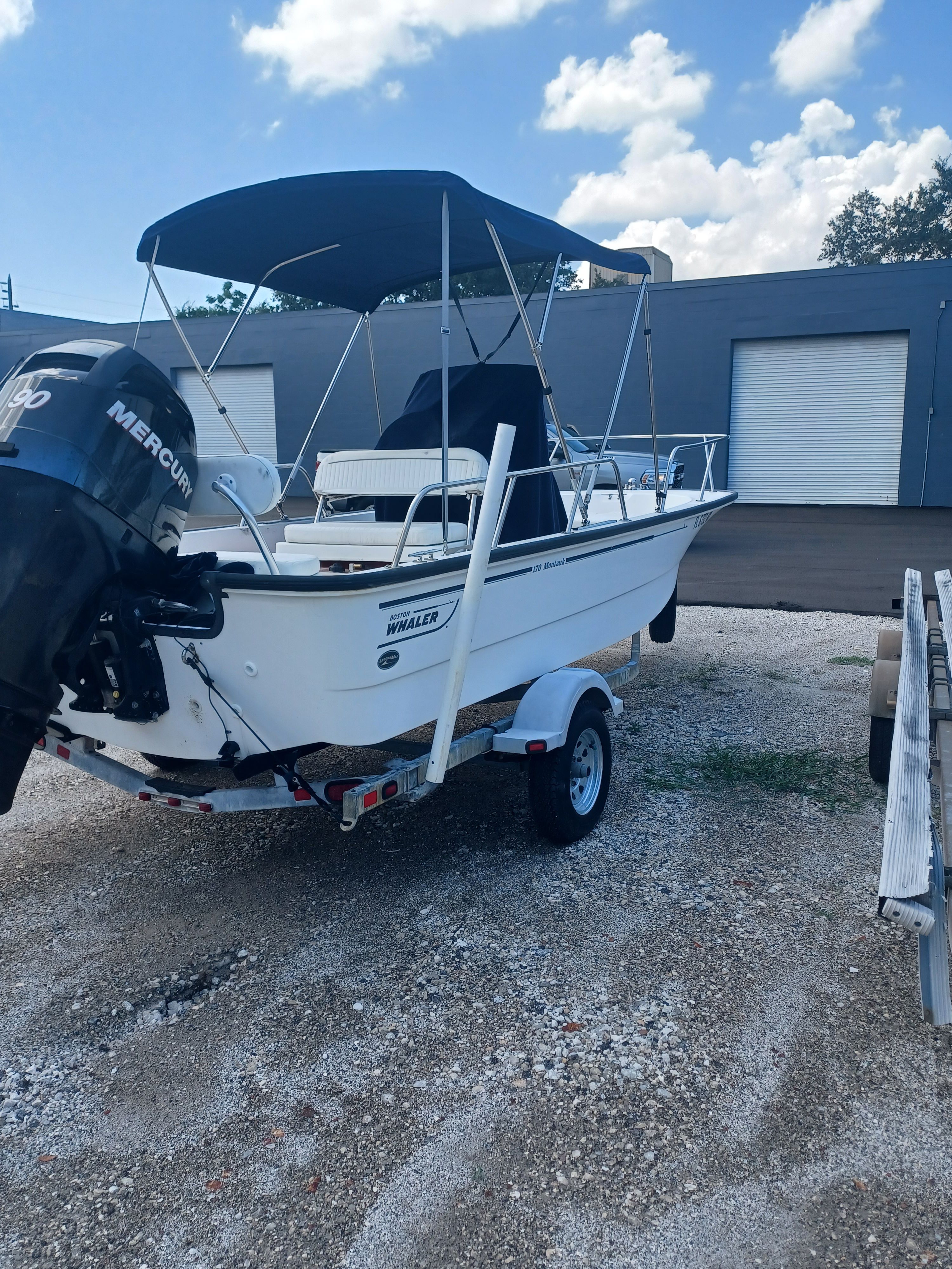 A 2008 Boston Whaler 170 Montauk on a trailer. It features a blue sunshade.