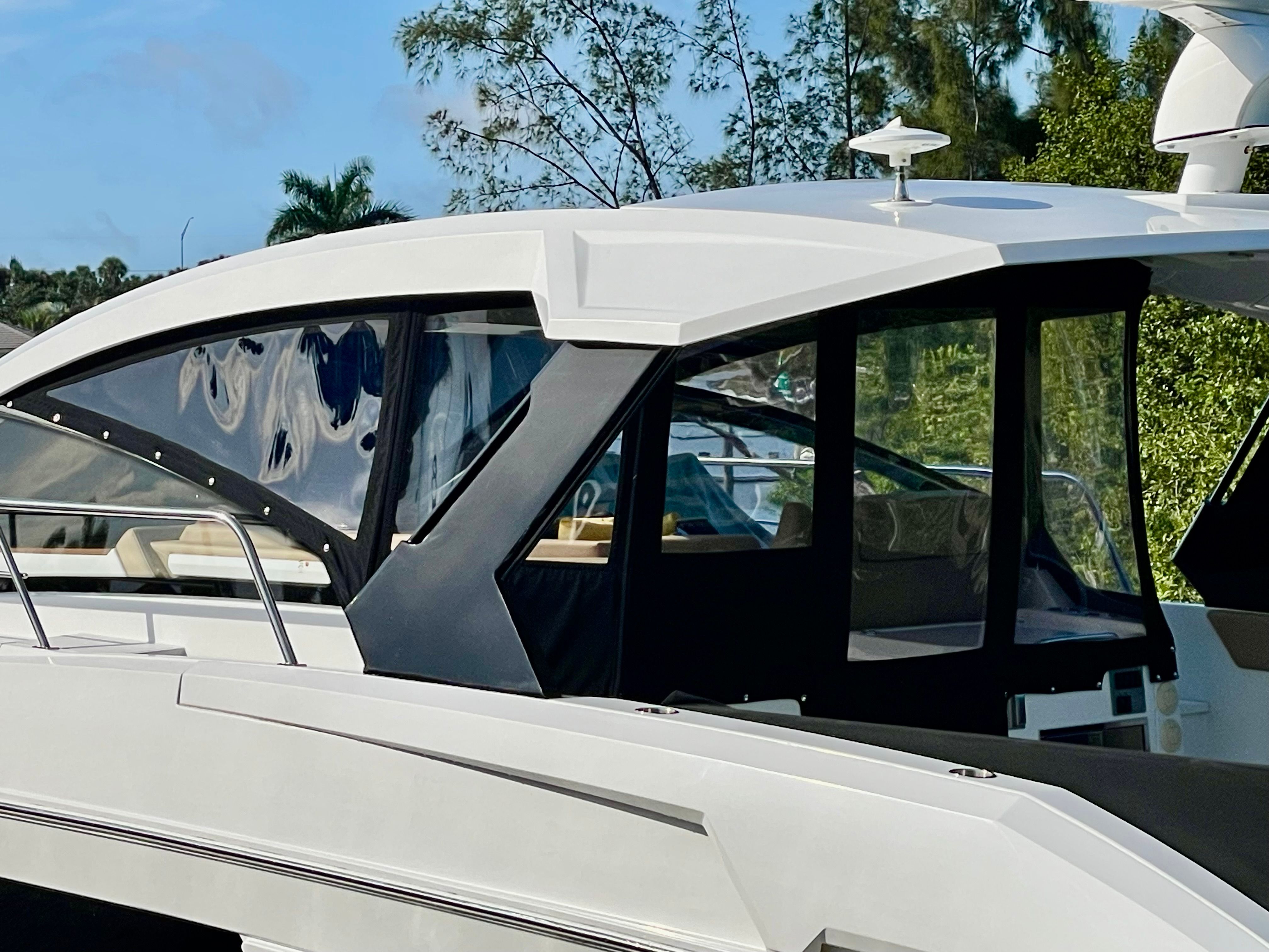 A sleek white boat with modern windows and an enclosed cockpit area.