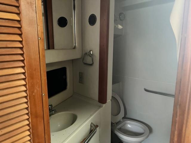 1990 Sea Ray 380 Aft Cabin bathroom with sink, mirror, and toilet.
