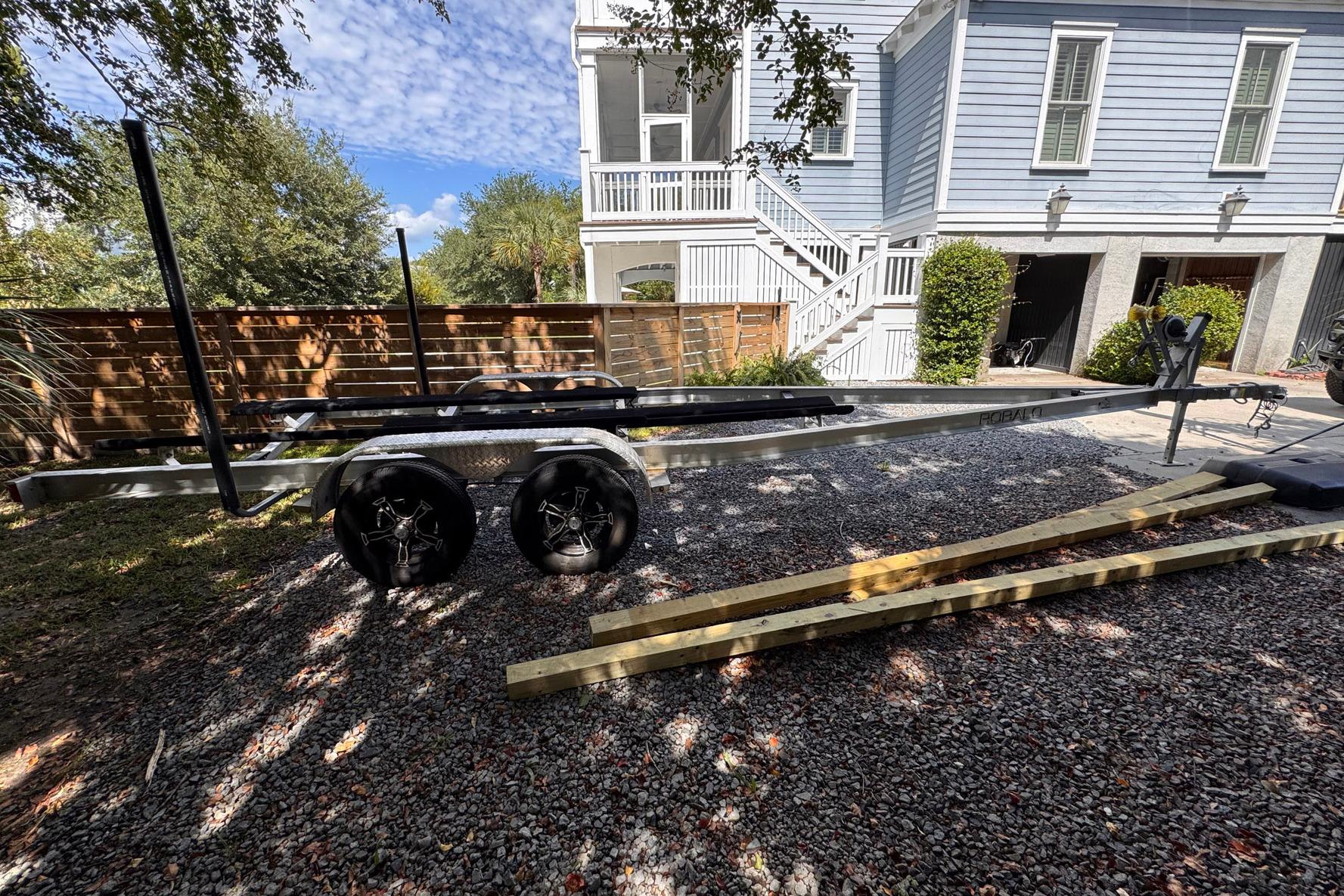Trailer for 2021 Robalo 246 Cayman boat parked on gravel driveway.