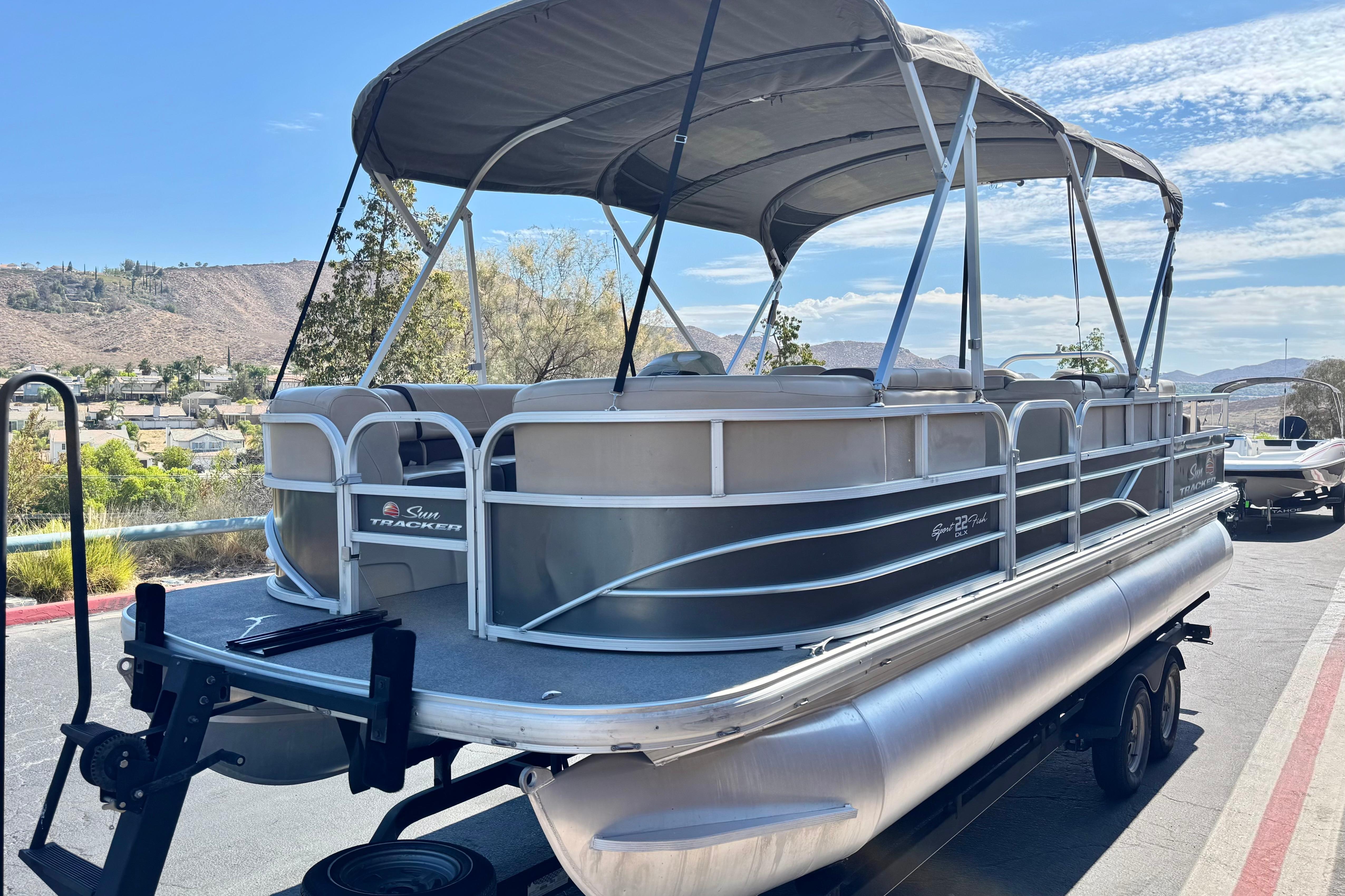 2018 Sun Tracker SportFish 22 DLX pontoon boat on trailer, scenic background.