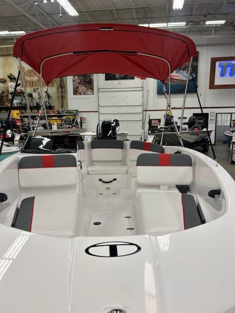2025 Tahoe T16 boat with red canopy in showroom, featuring spacious seating and modern design.