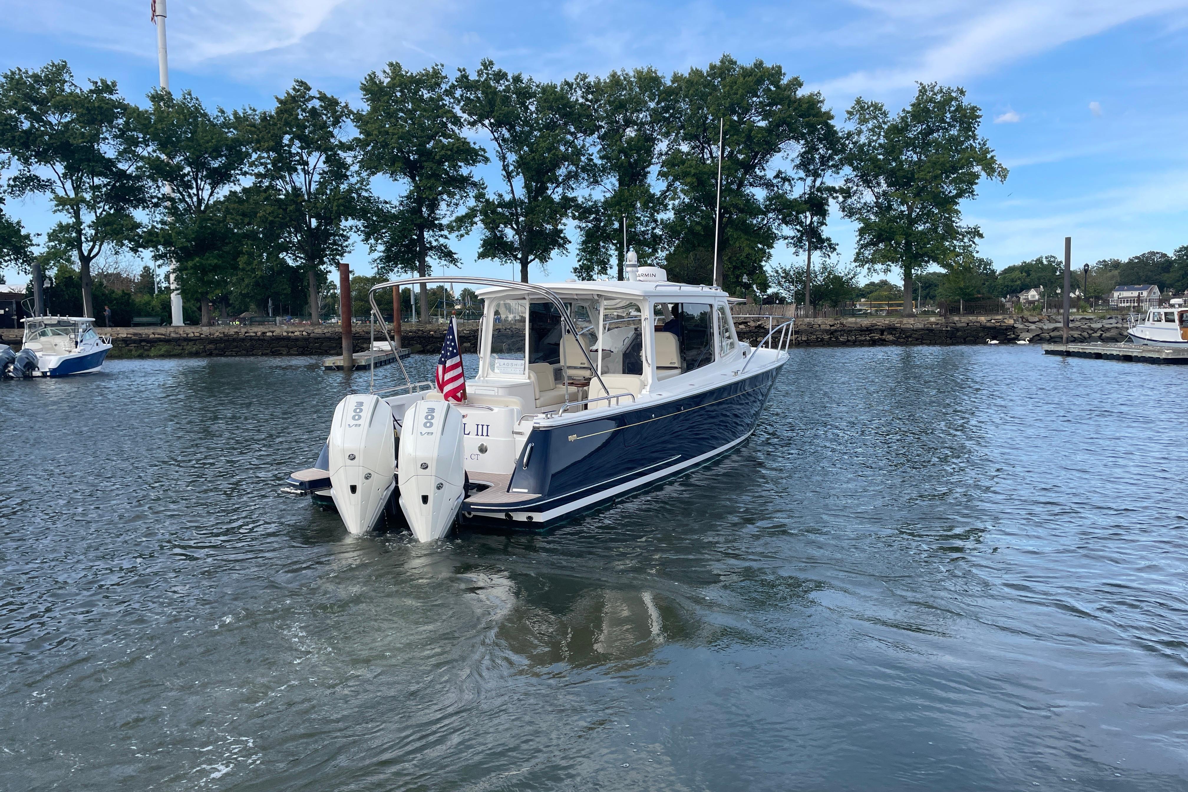 2023 MJM 35 boat with dual engines on a calm waterway, surrounded by trees.