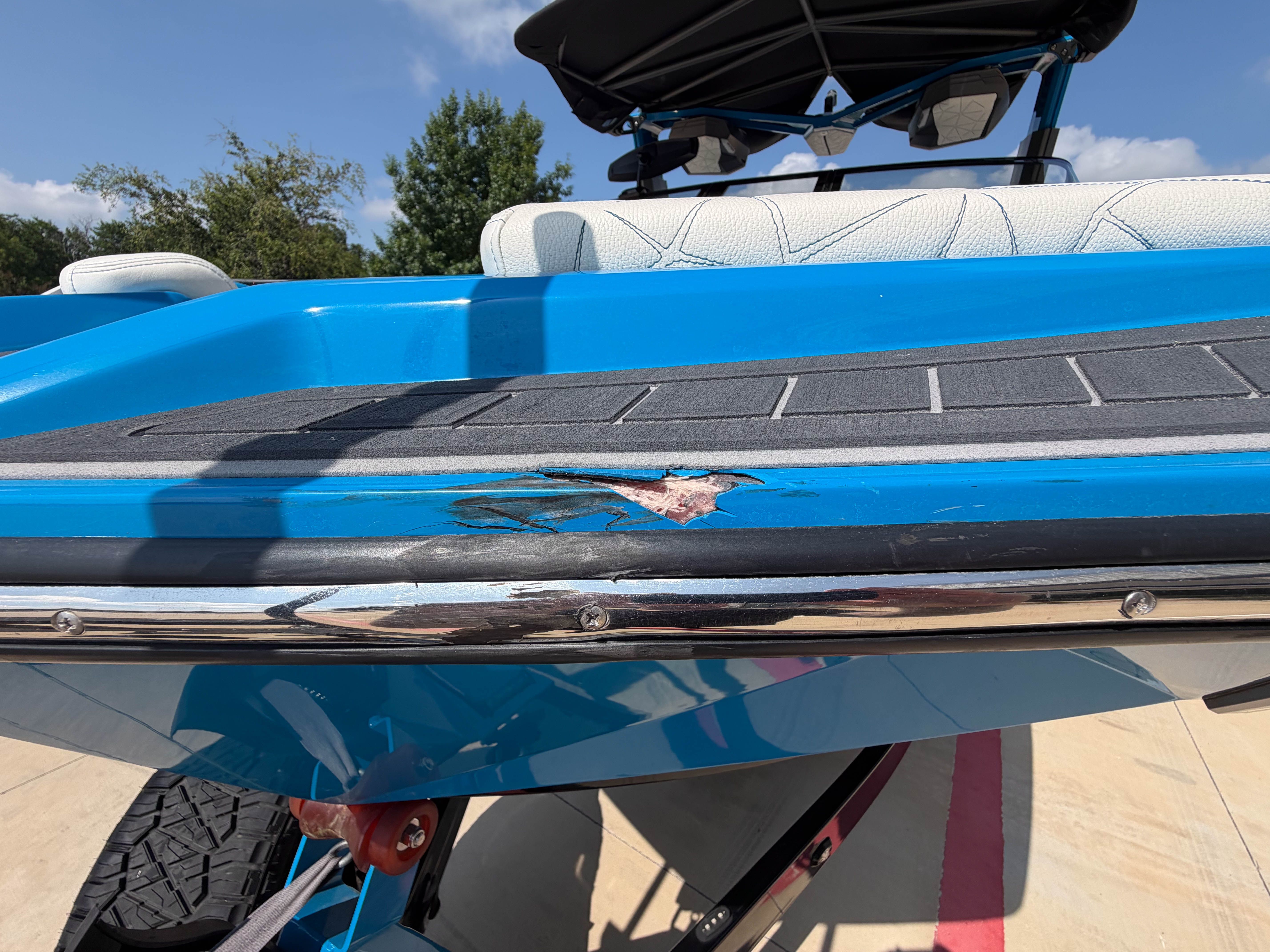 Close-up of a blue boat with scratches on the hull, on a trailer.