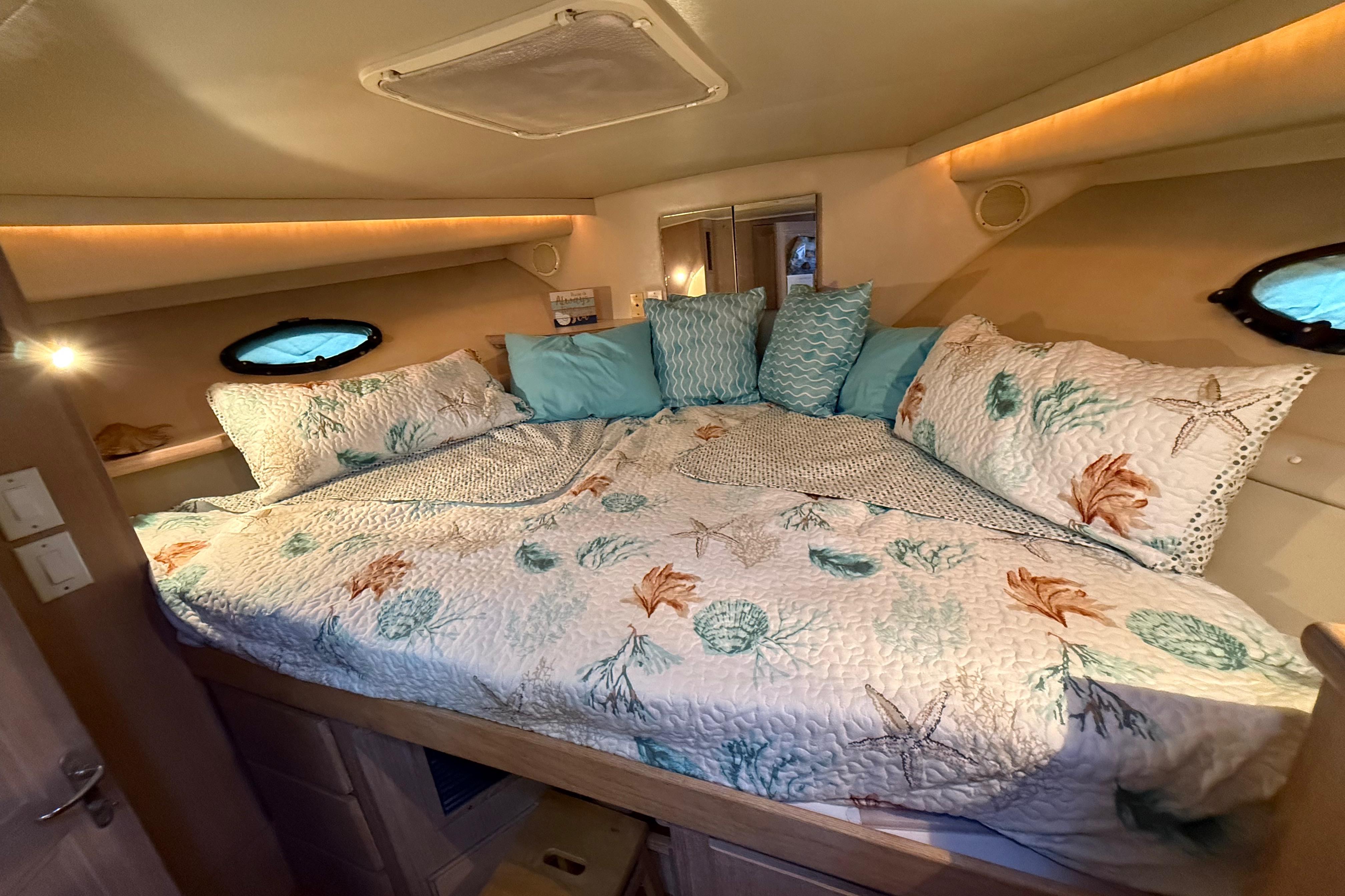 Cozy bedroom in 1991 Californian 55 Cockpit Motor Yacht with nautical-themed bedding.