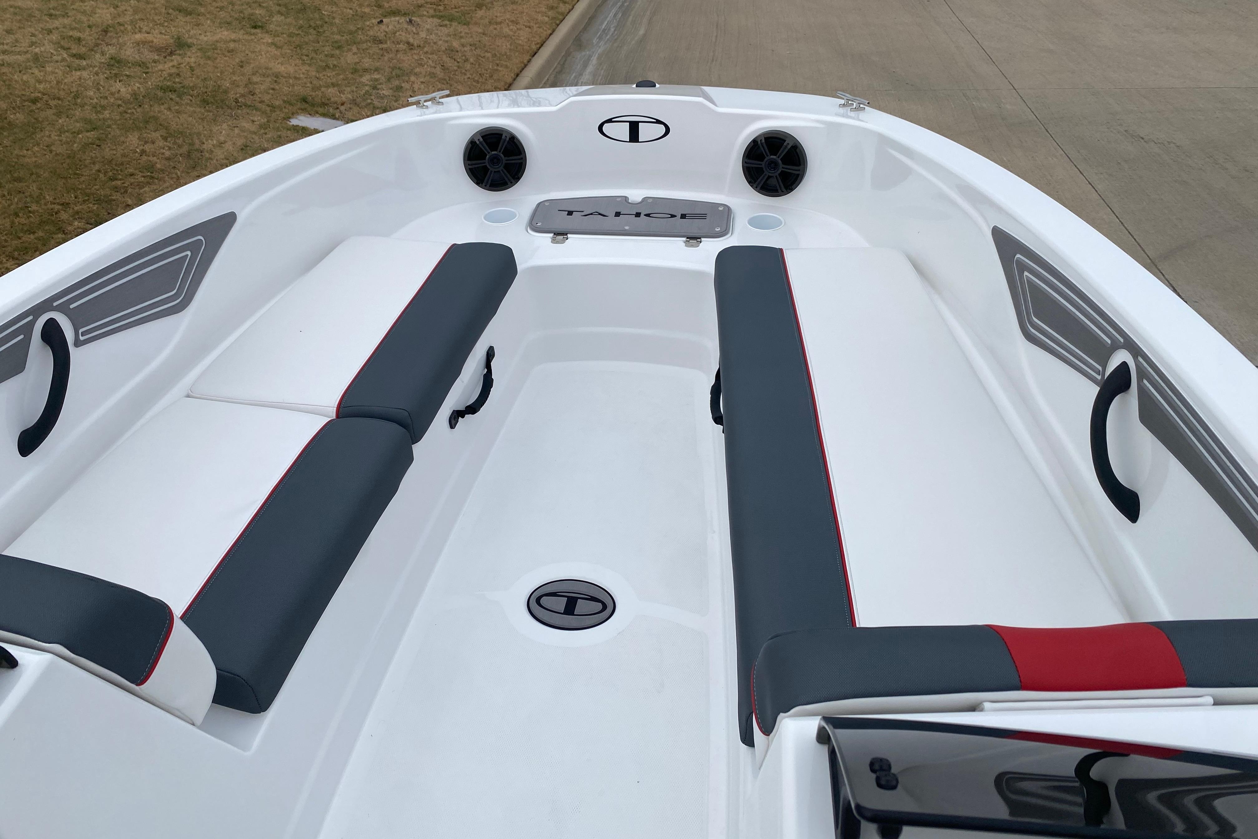 2026 Tahoe T21 boat interior with gray and white seating, red accents, and speaker system.