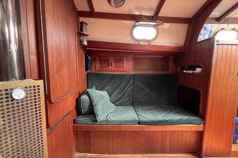 Interior of 1980 Ta Shing Baba 30 sailboat with wooden paneling and green cushions.