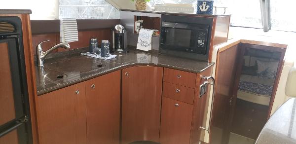 2010 Meridian 441 Sedan yacht kitchen with microwave, sink, and wooden cabinetry.