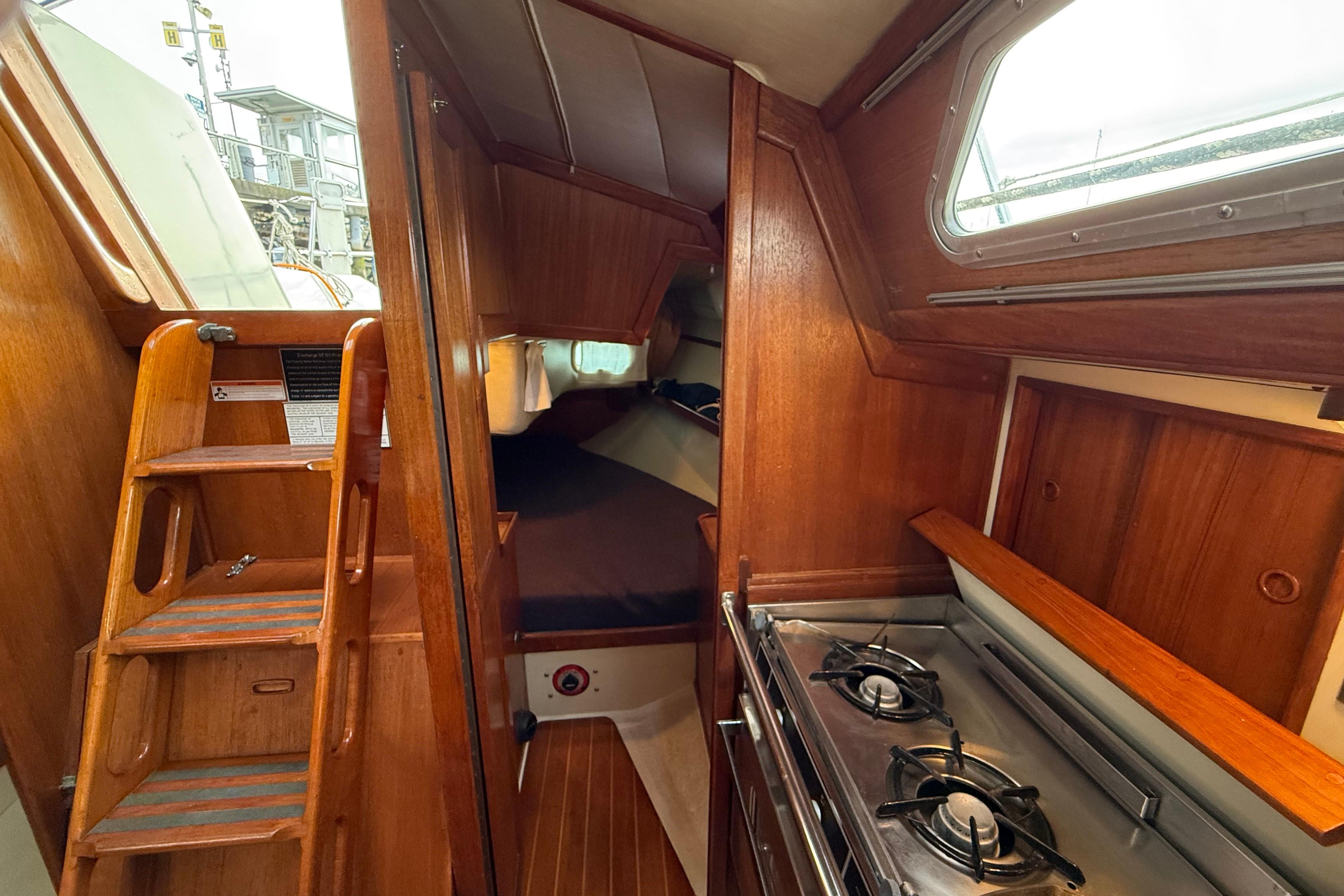 Interior of 1988 Ericson 32-200 sailboat with wooden cabinetry and compact kitchen.