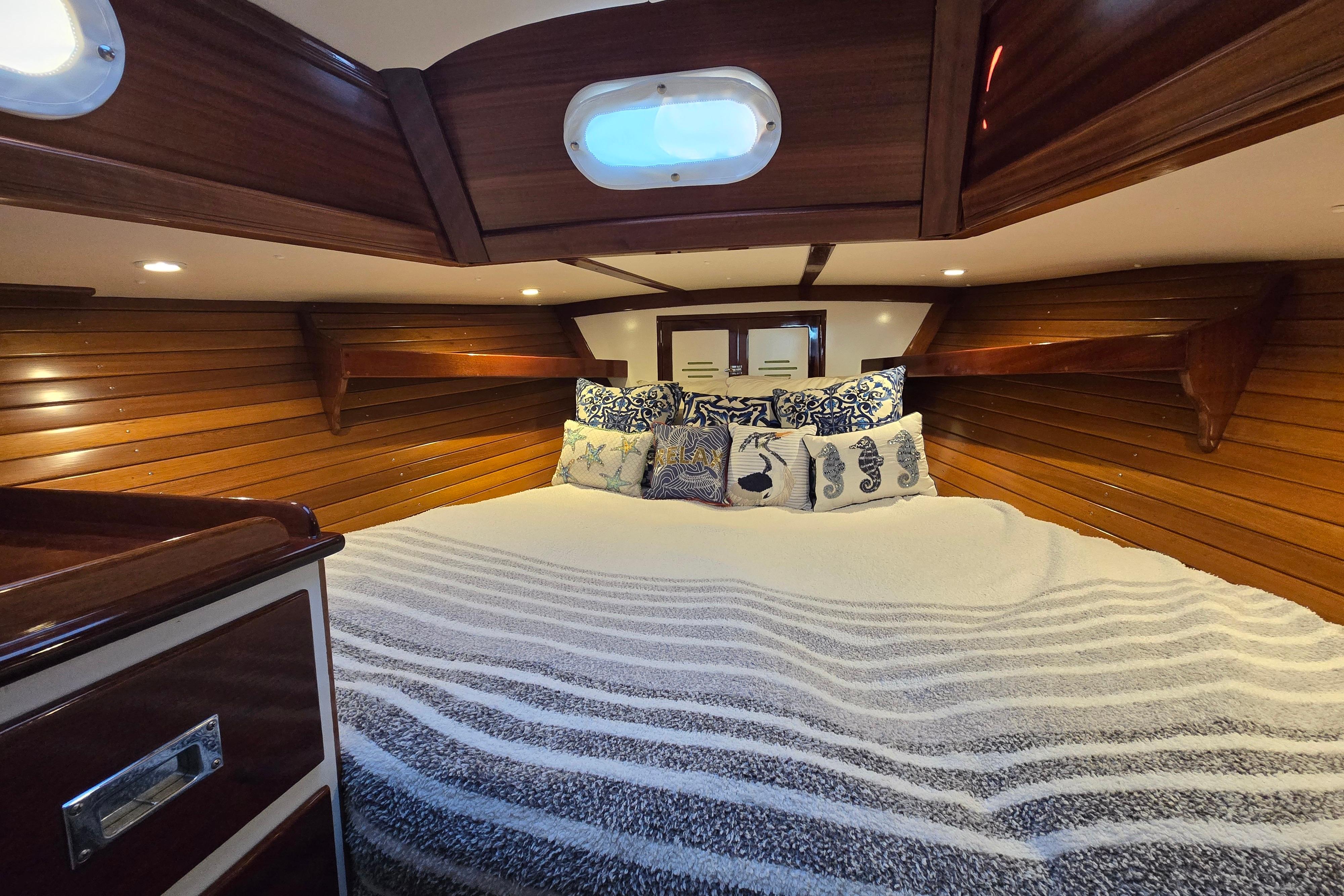 Cozy cabin interior of 1970 Hinckley Bermuda 40 sailboat with wooden paneling and plush bedding.