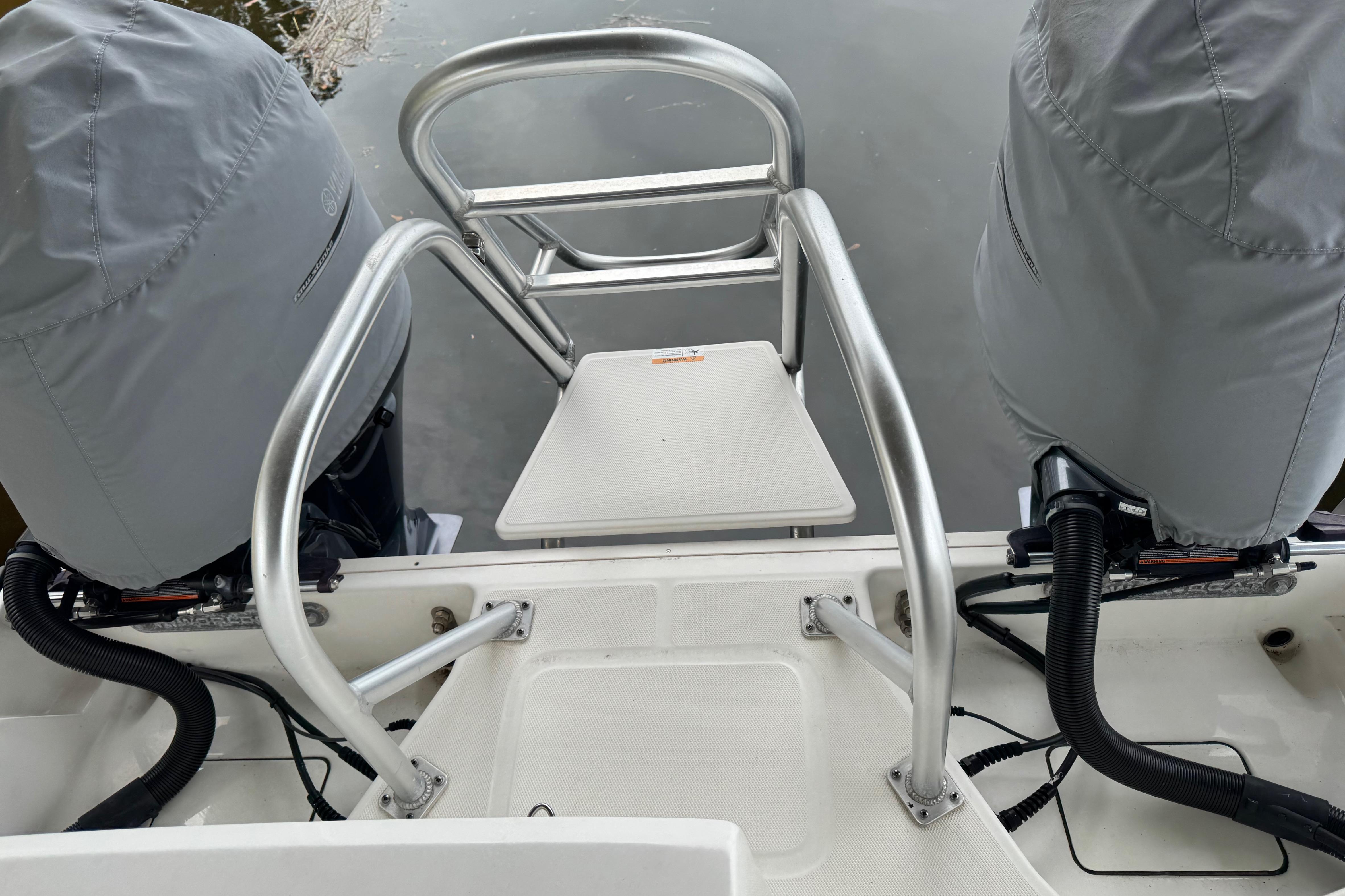 2023 World Cat 280 DC-X boat with dual covered engines and rear boarding ladder.