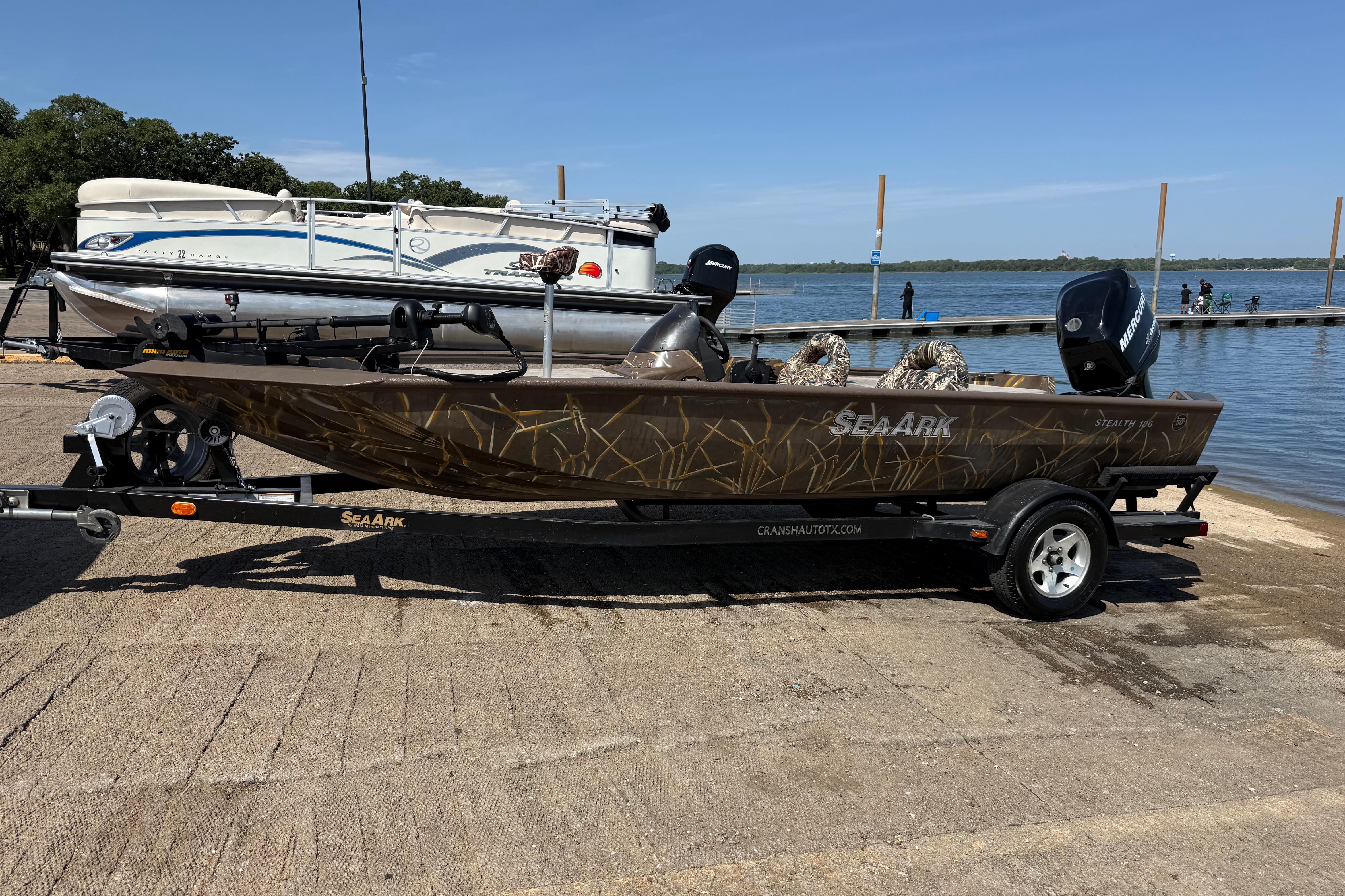 2010 SeaArk Stealth 190 boat on trailer by a lakeside dock.