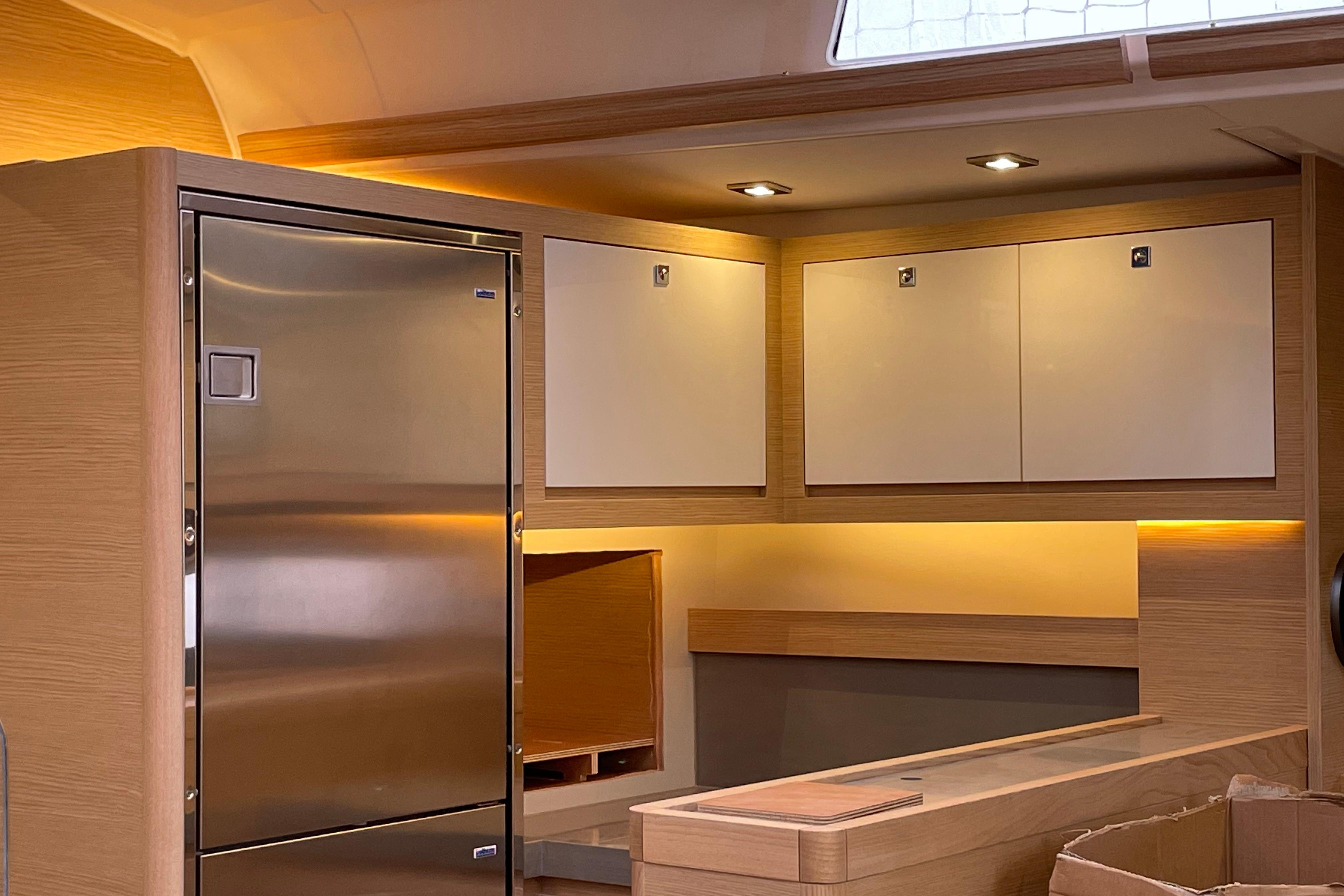 Modern interior of 2022 Dufour 530 yacht with sleek cabinetry and stainless steel fridge.