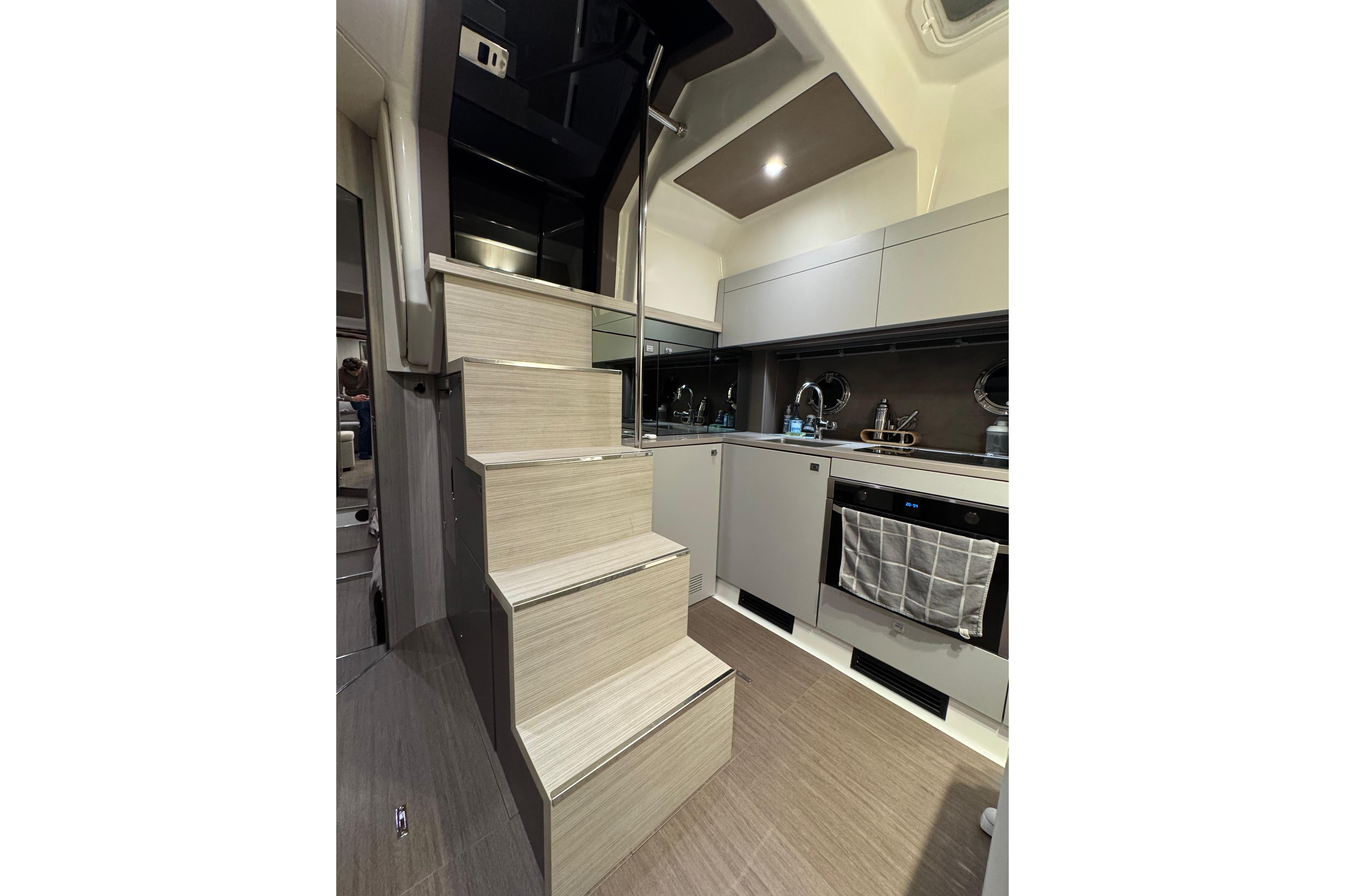 Modern kitchen interior of 2019 Cranchi M 44 HT yacht with sleek cabinetry and stairs.