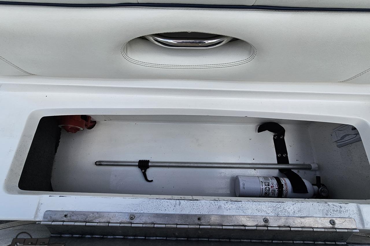 Storage compartment in a 2010 Cobalt 232 WSS boat with fire extinguisher and rod.