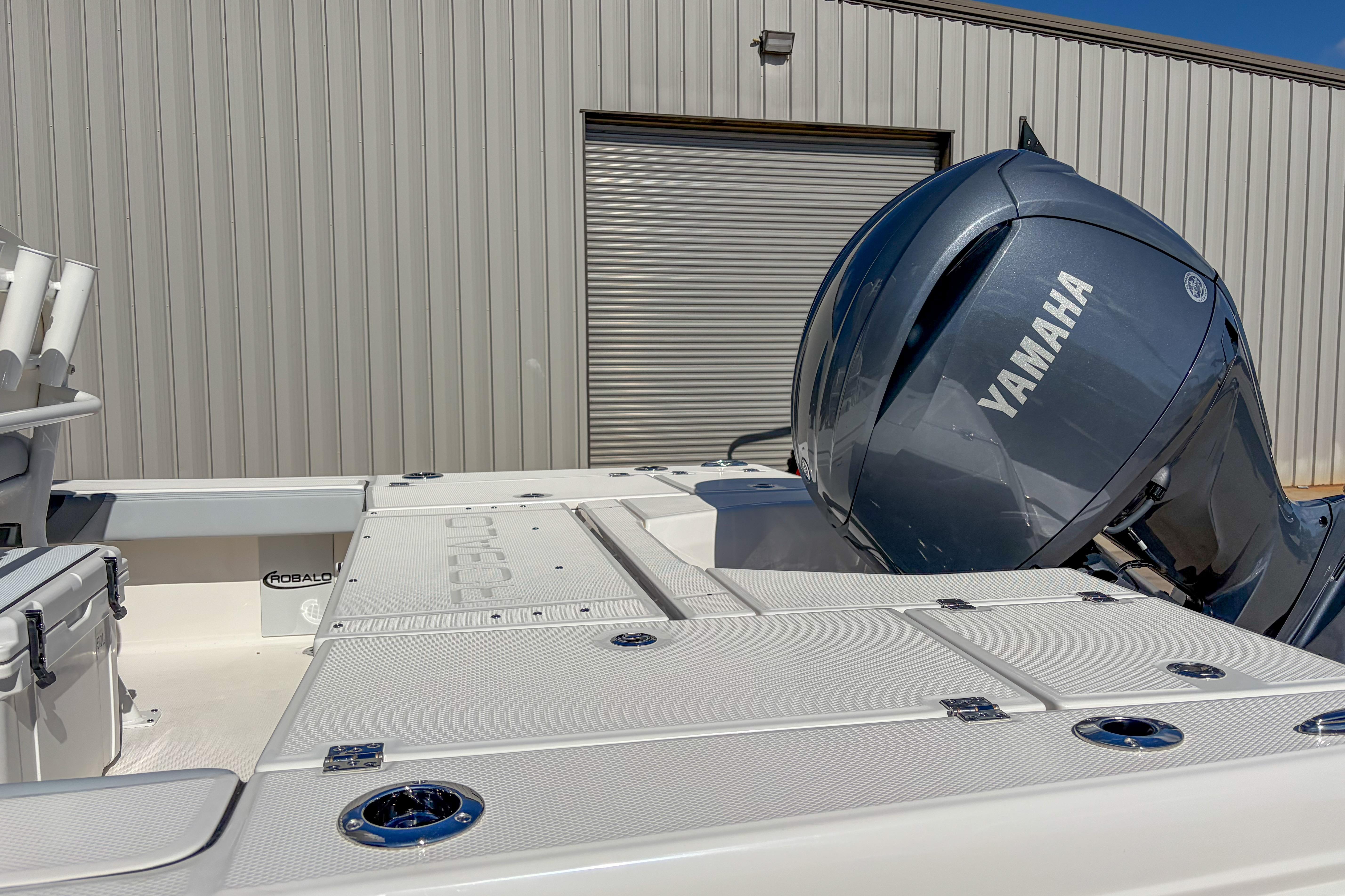 2025 Robalo 226 Cayman boat with Yamaha engine, docked near a metal building.