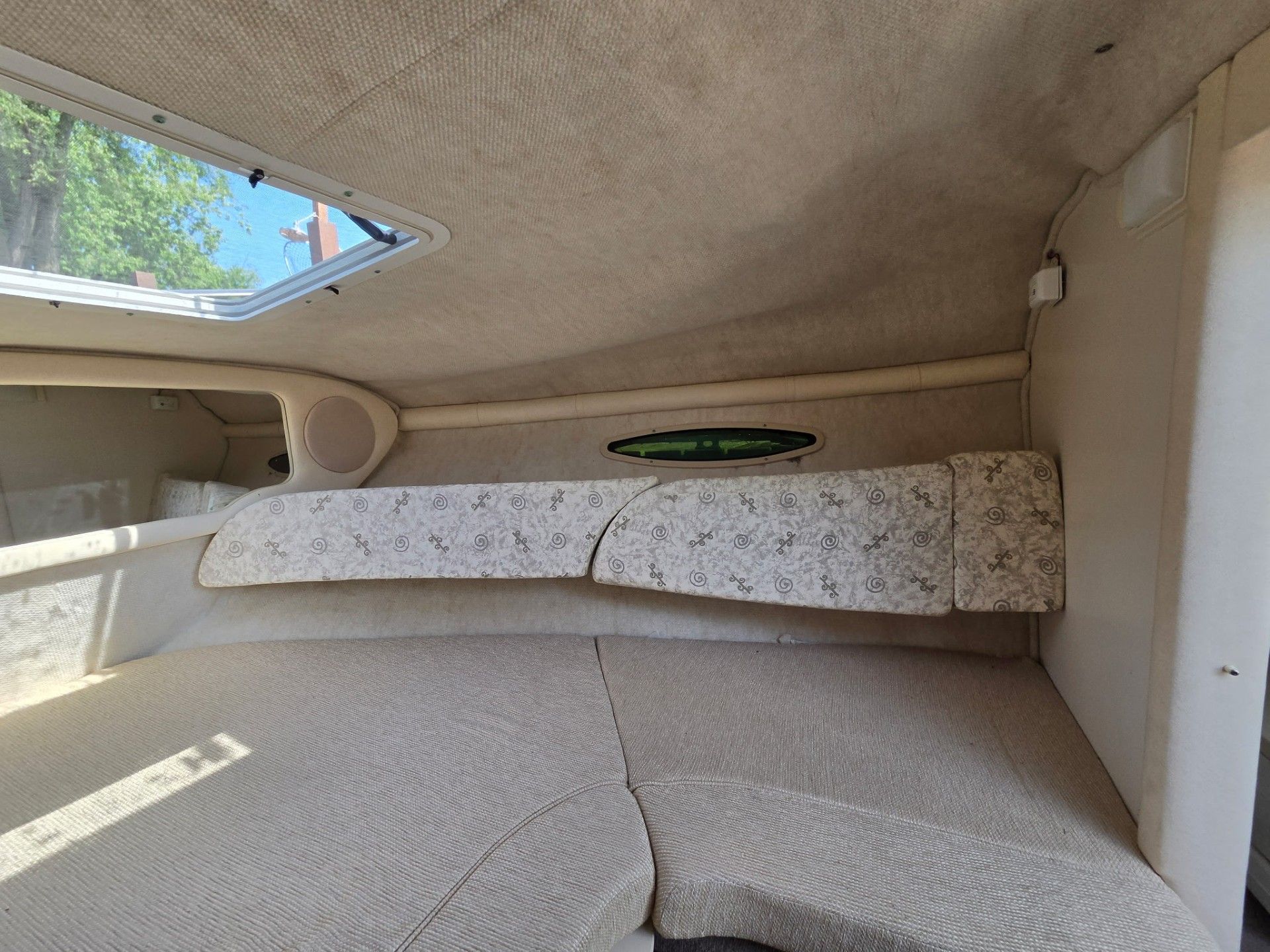Interior of the 2002 Sea Ray 225 Weekender with cushioned seating and a window.