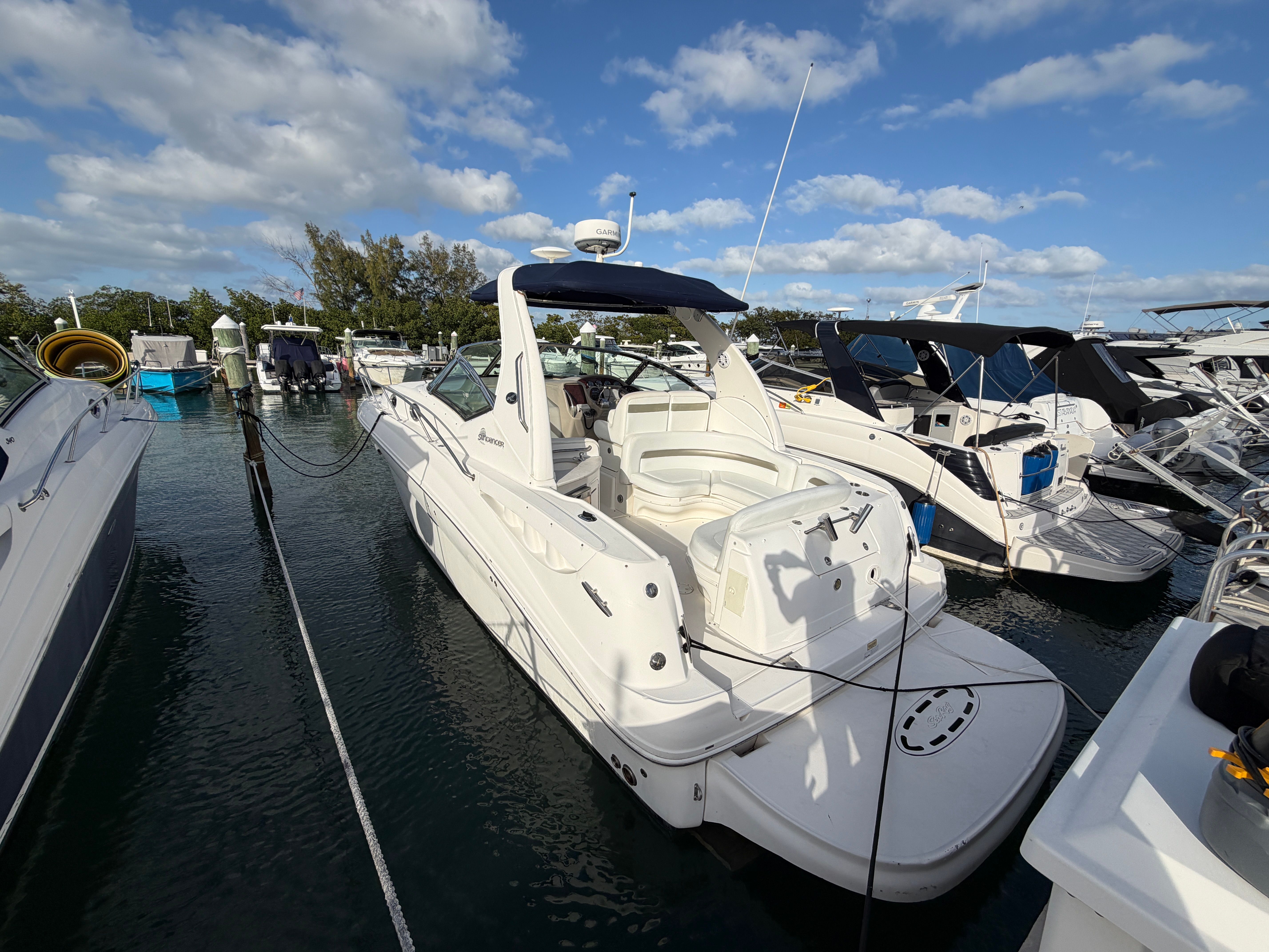 A 2006 Sea Ray Sundancer 320 is docked in the water, surrounded by other boats.
