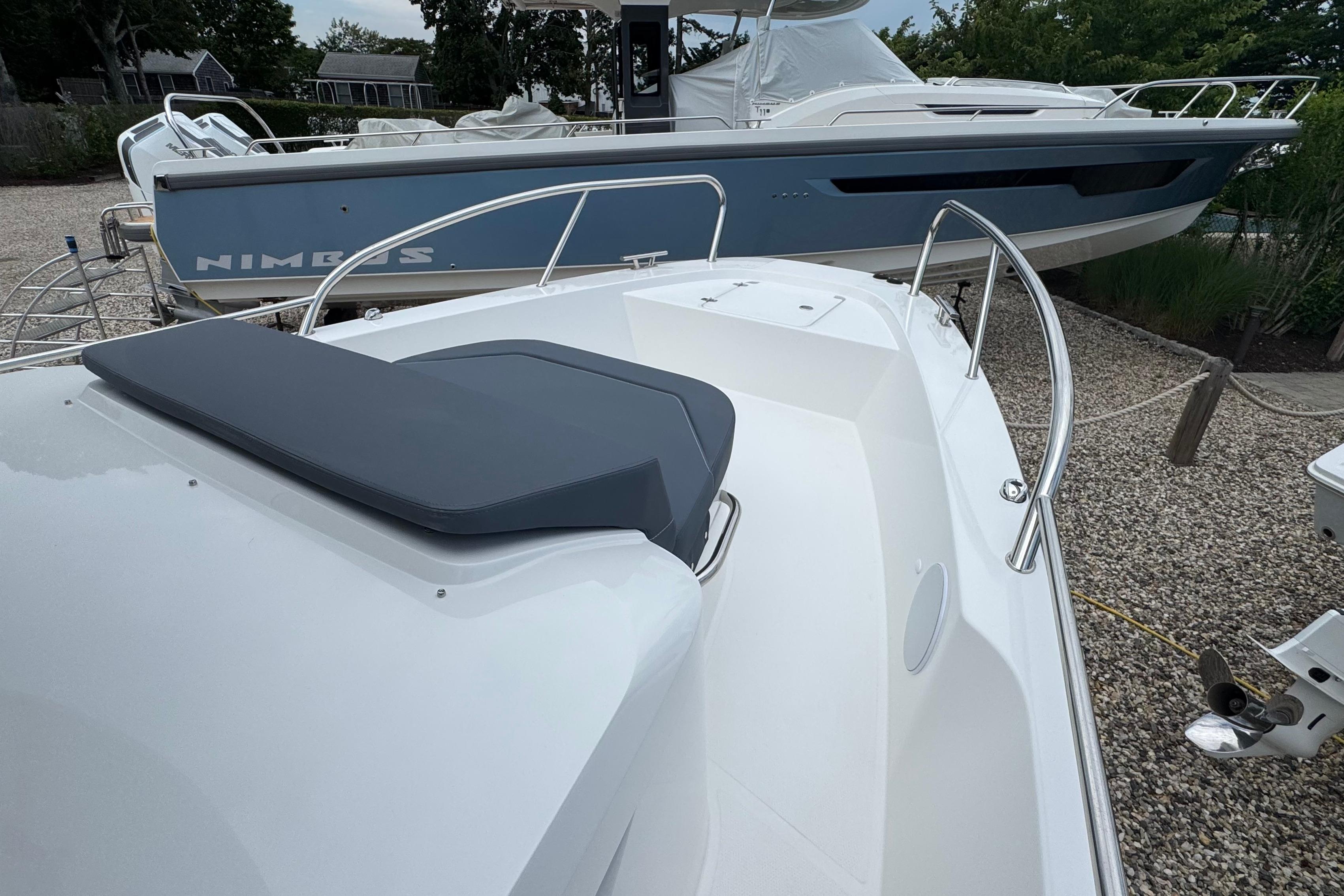 A 2026 Nimbus Commuter 9 boat is on a gravel lot next to another boat.