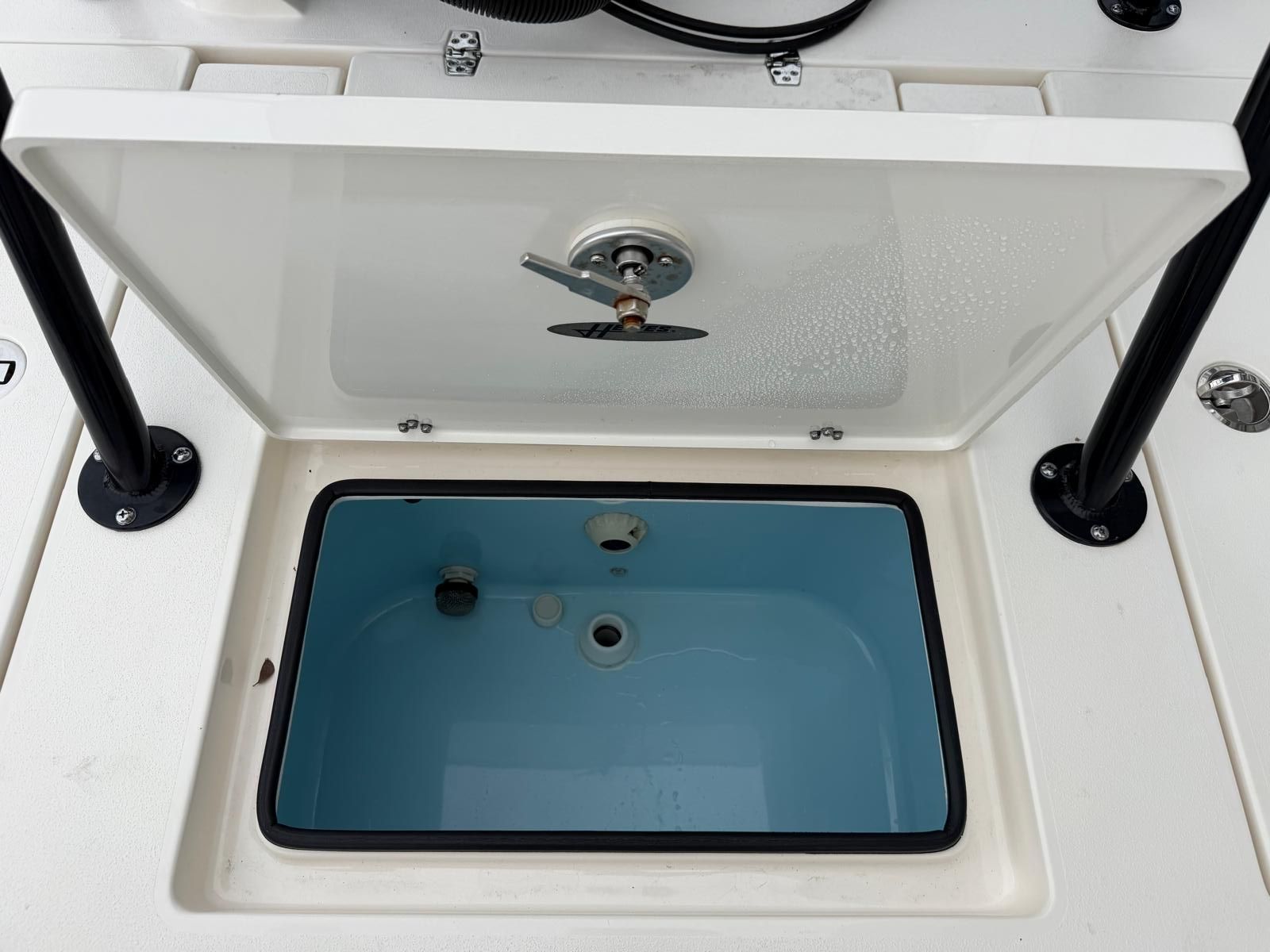 An open storage compartment on a boat with blue interior and black supports.