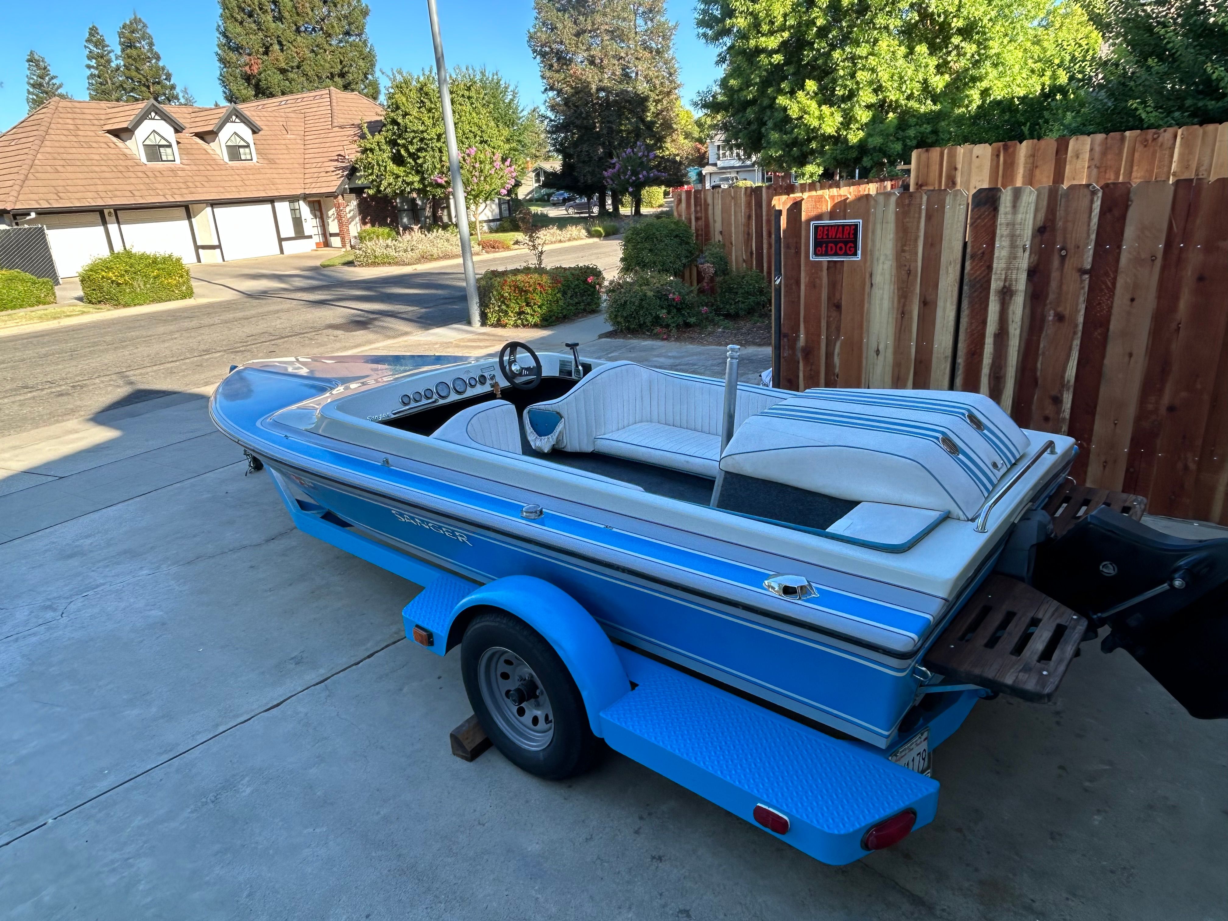 A blue 1988 Sanger Ski Tug on a trailer in a driveway.