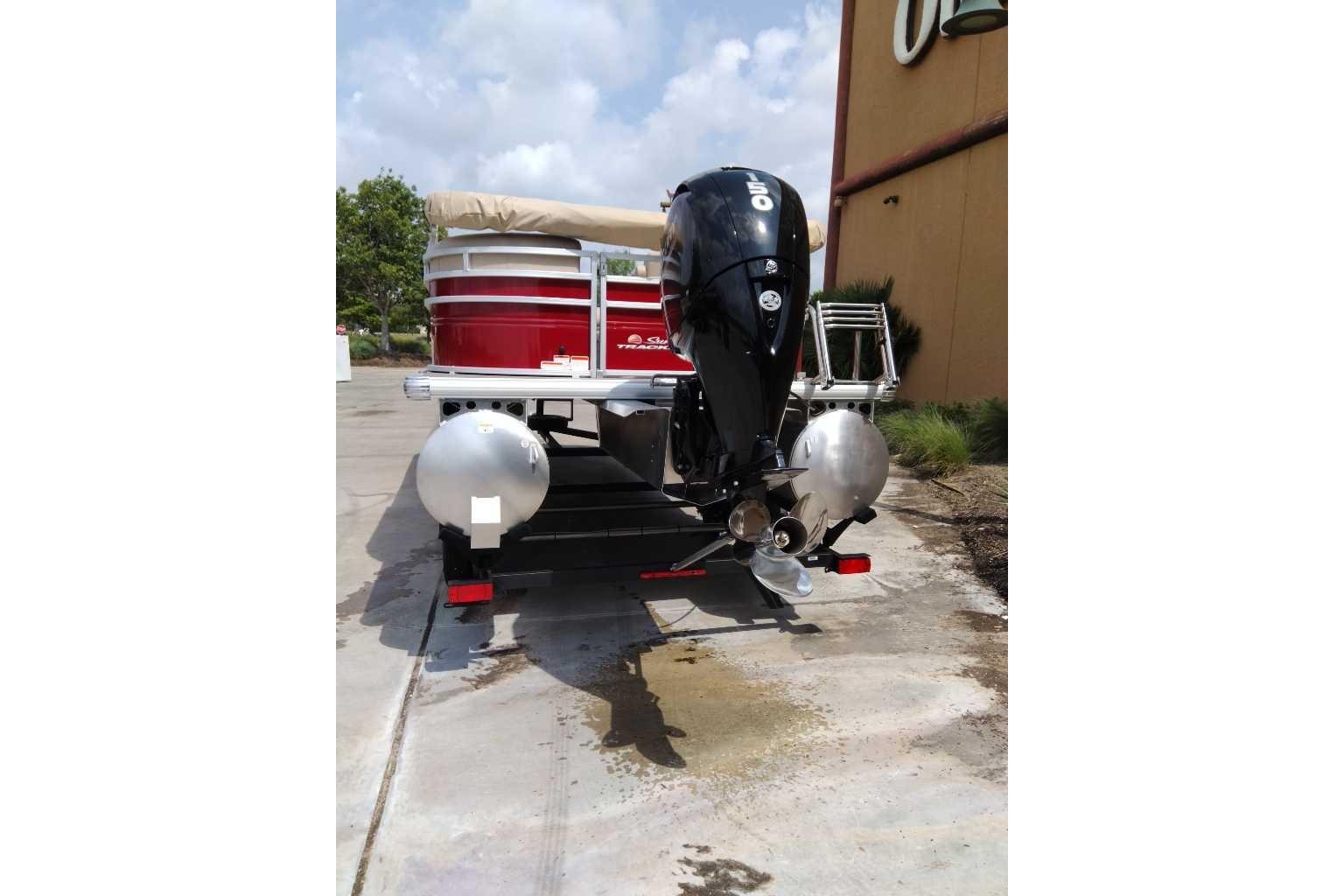 2025 Sun Tracker Party Barge 22 DLX pontoon boat with outboard motor, parked outdoors.