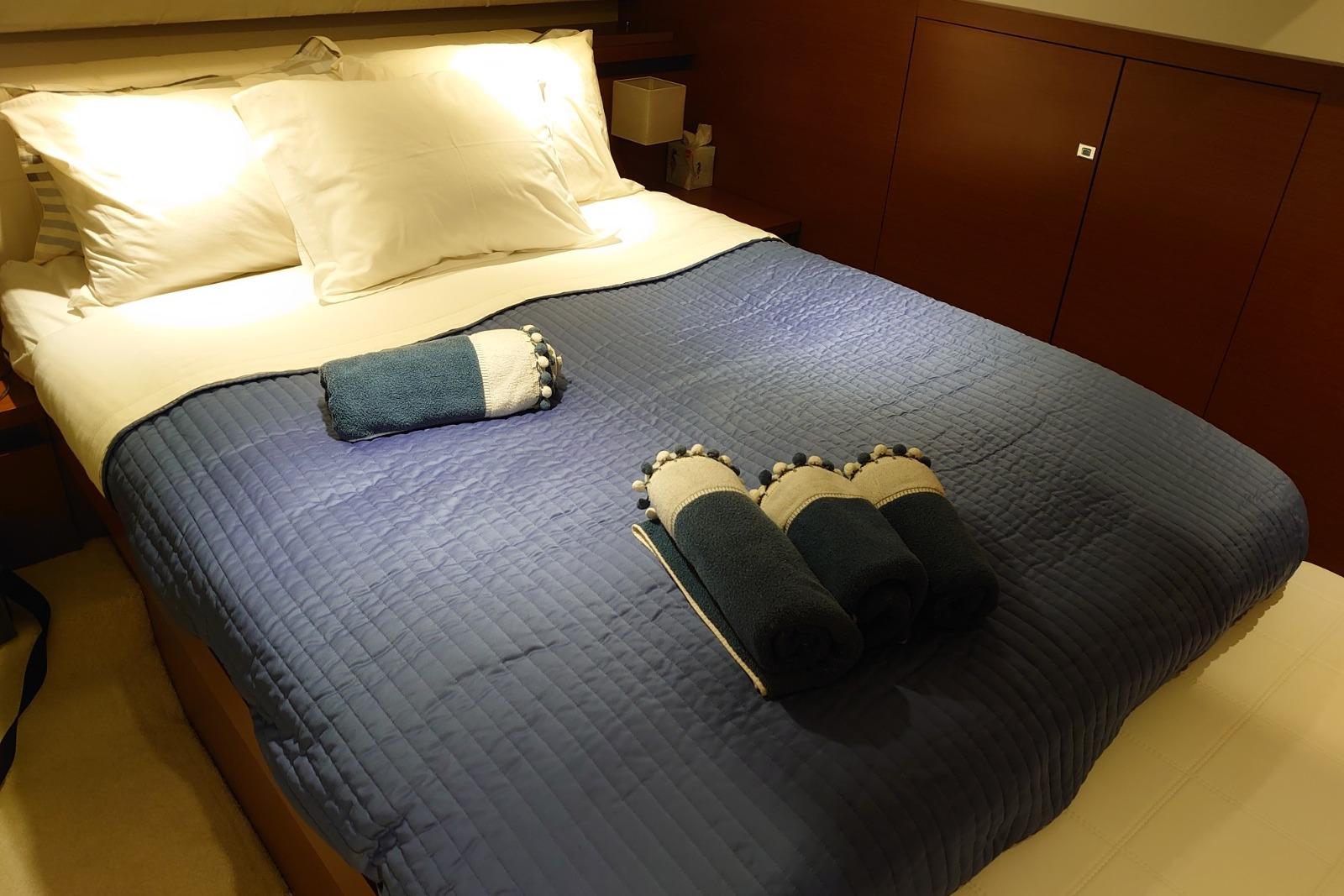 Luxurious cabin bed with blue quilt and neatly arranged towels on a 2013 Prestige 450S yacht.