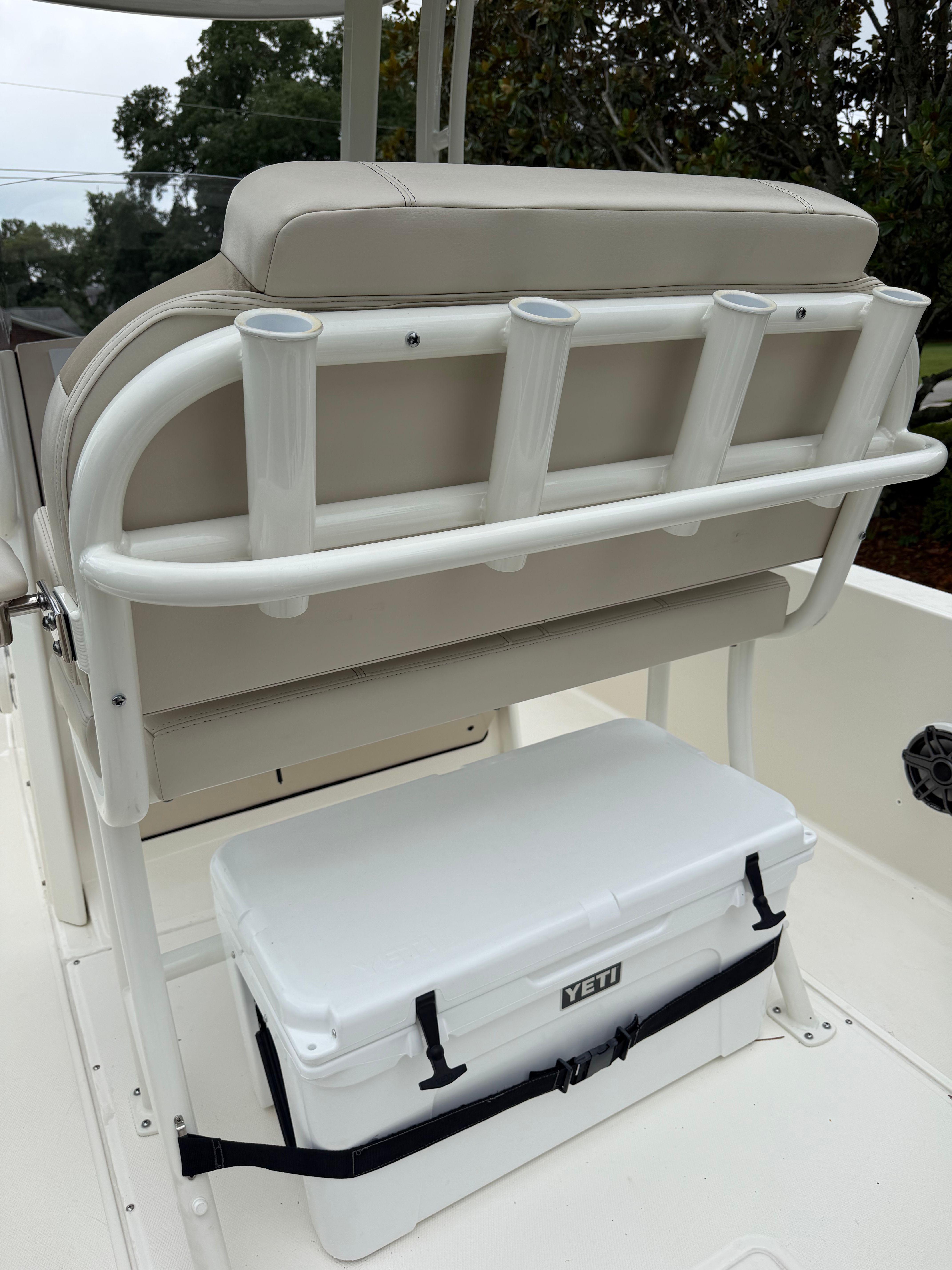 The back of a boat seat with fishing rod holders and a cooler underneath.
