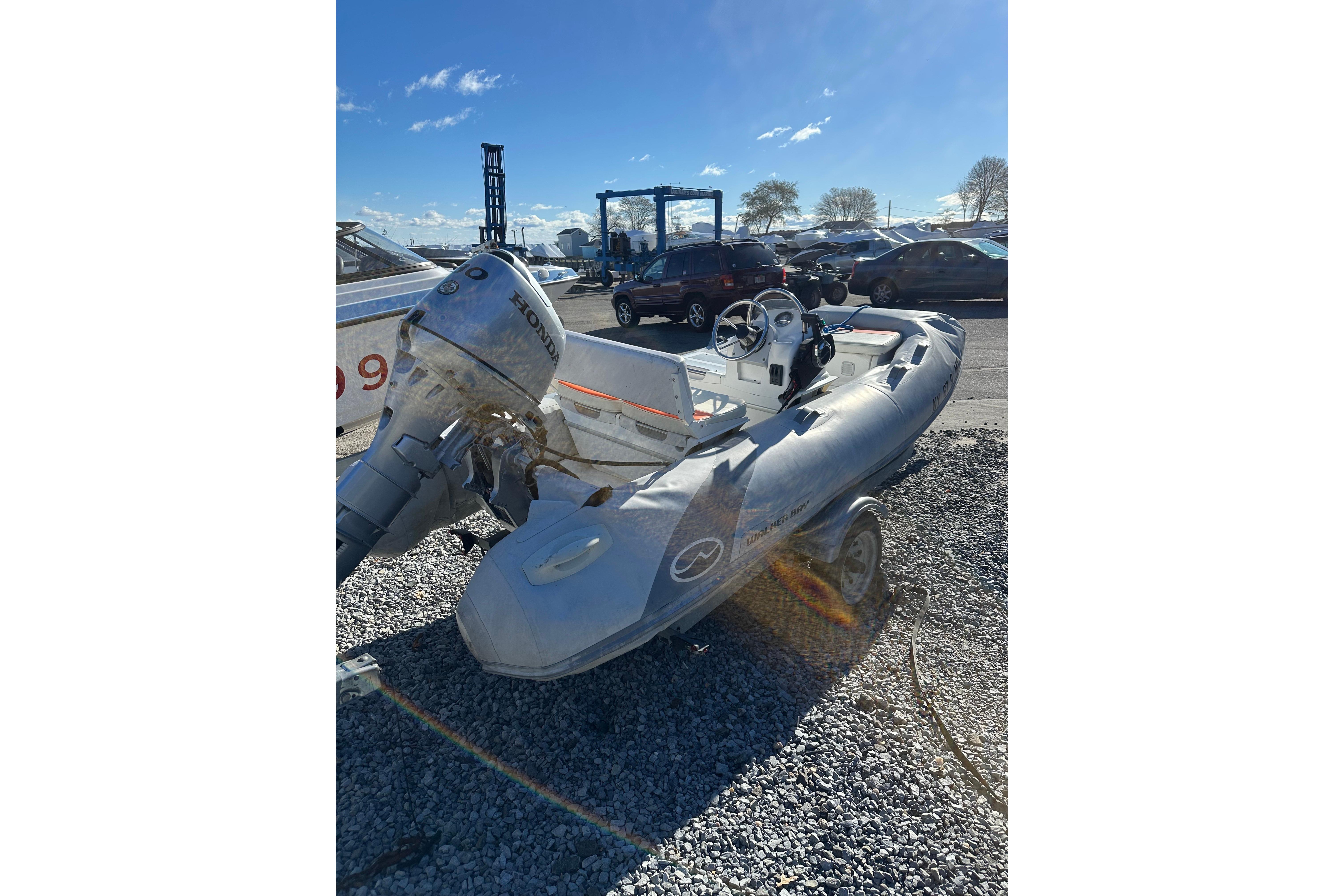 2016 Walker Bay 325 ST inflatable boat with Honda outboard motor on gravel.