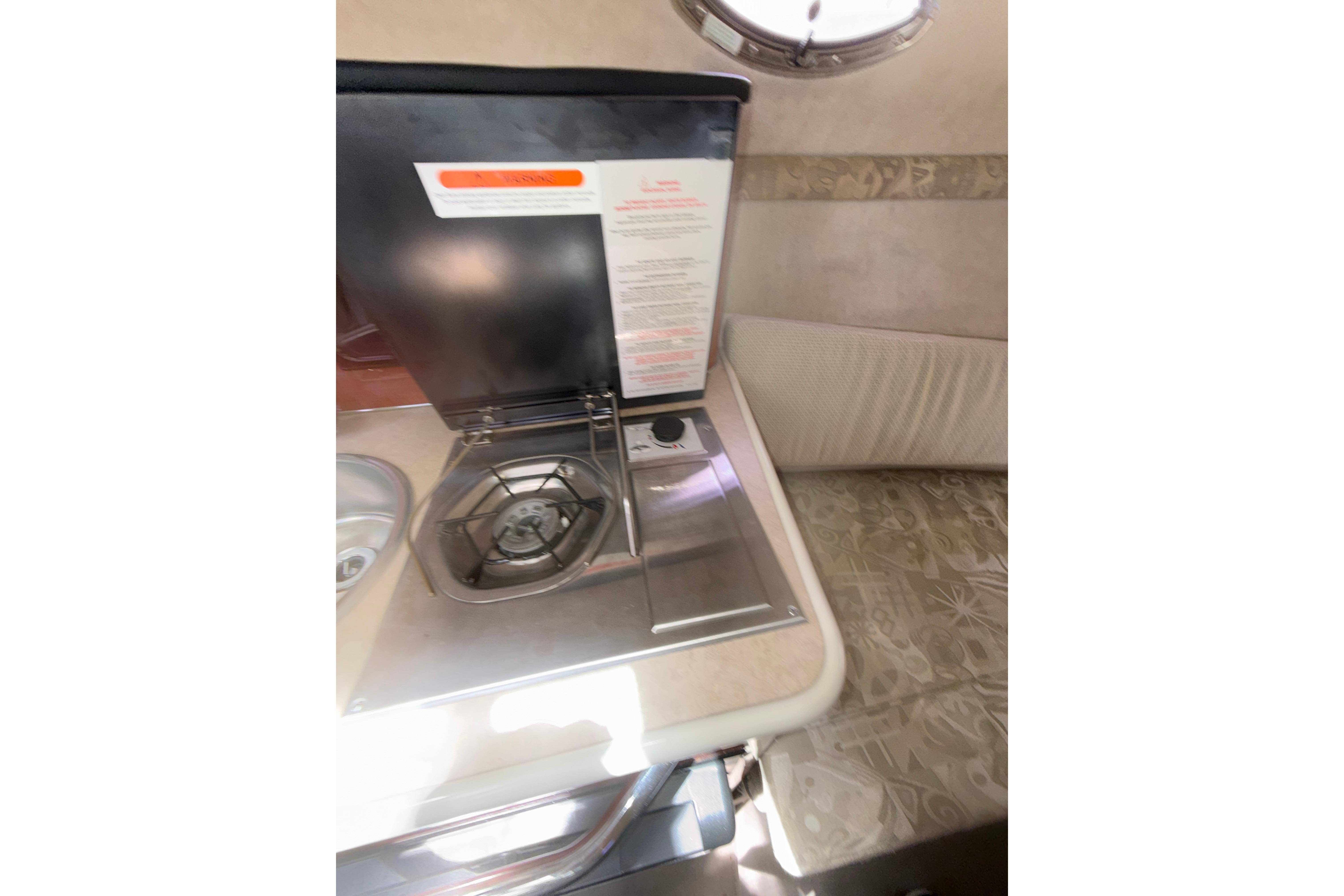 2004 Sea Ray 240 Sundancer interior with compact stove and seating area.