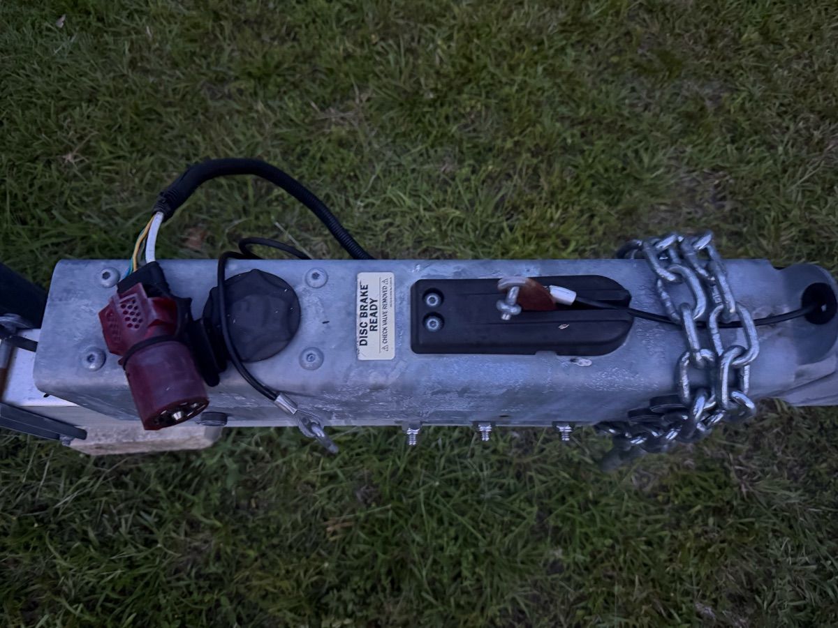 Close-up of a boat trailer with chains and cables on grass.