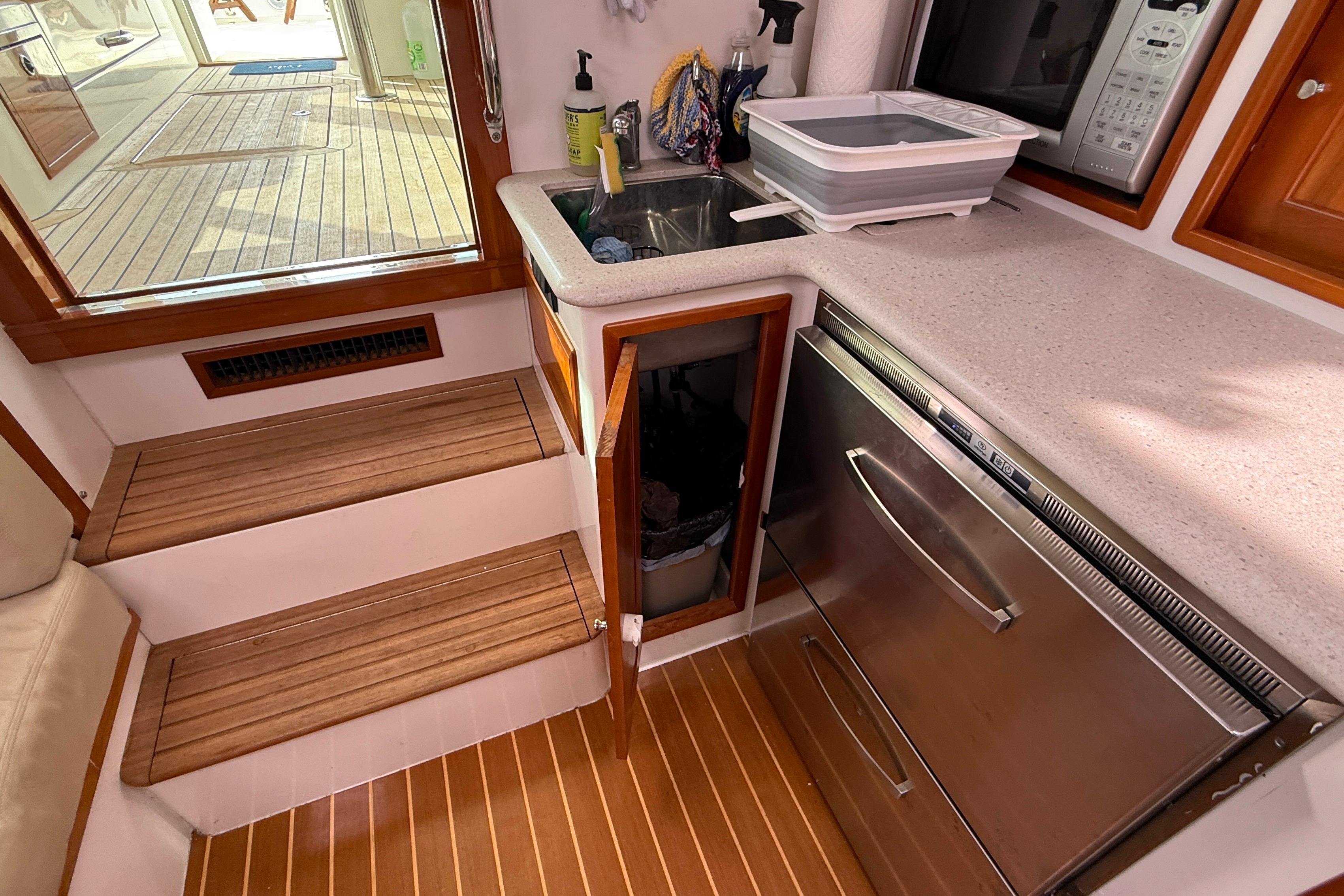 Compact galley in 2012 MJM 40z yacht with sink, microwave, and wooden steps.
