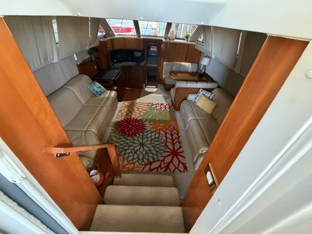 Interior of a 2005 Carver 44 Cockpit Motor Yacht with beige sofas and a colorful rug.
