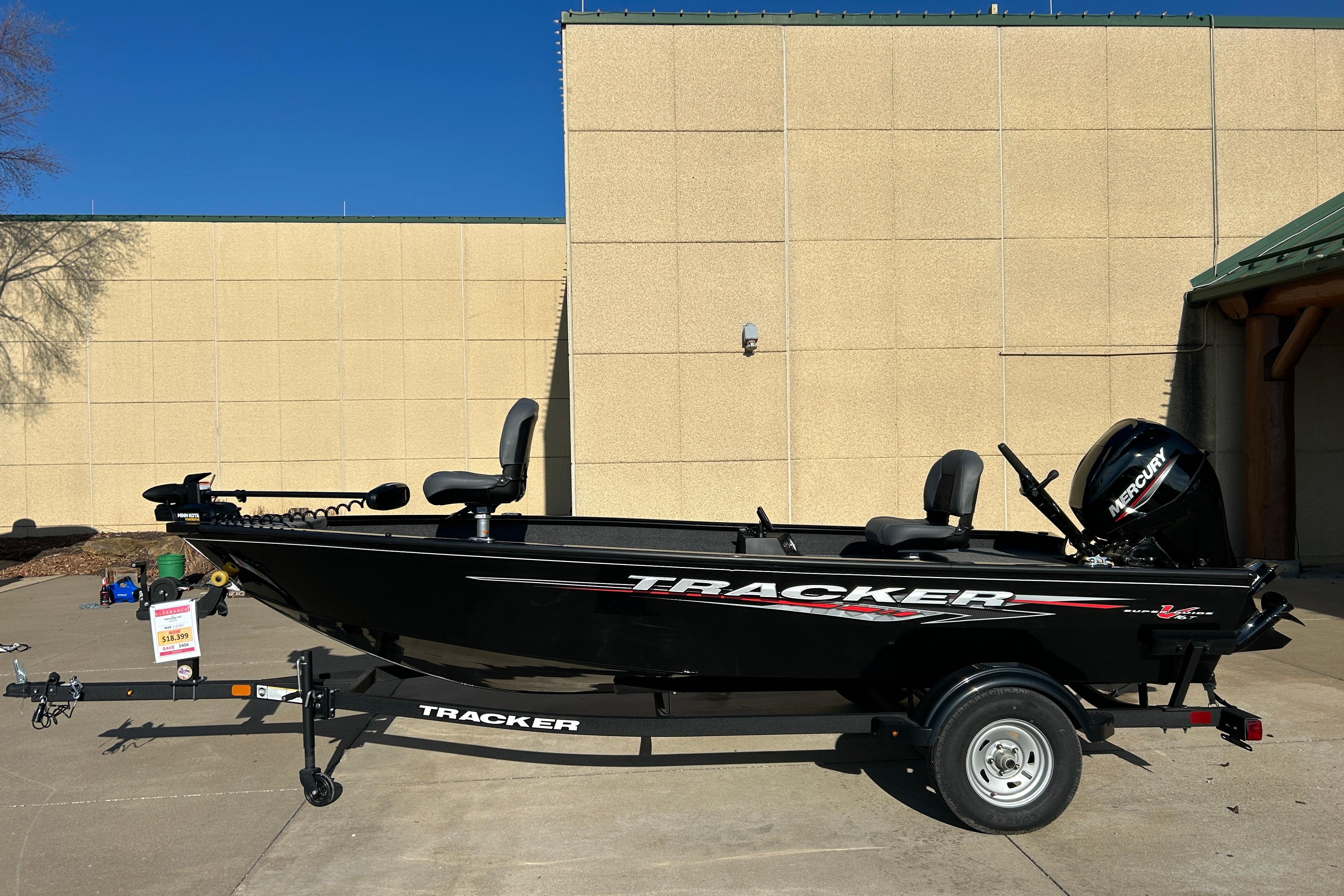2025 Tracker Super Guide V-16 T fishing boat on trailer, parked outdoors.