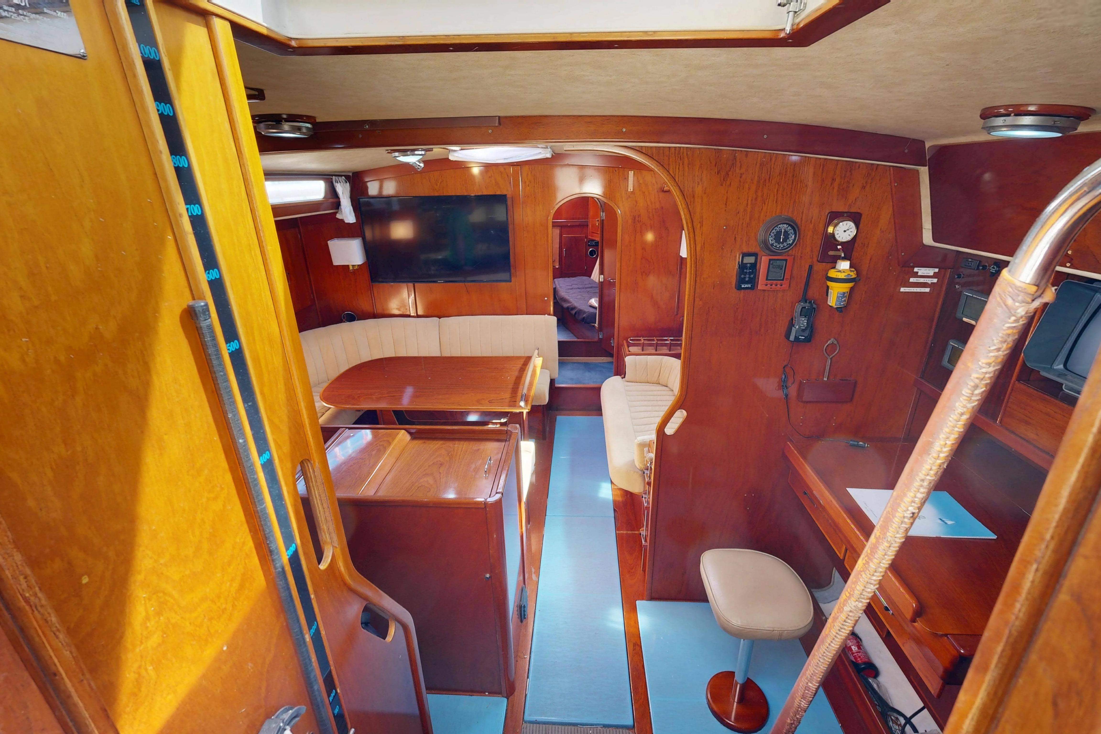 Interior of 1999 Amel Super Maramu 2000 yacht with wooden furnishings and seating area.