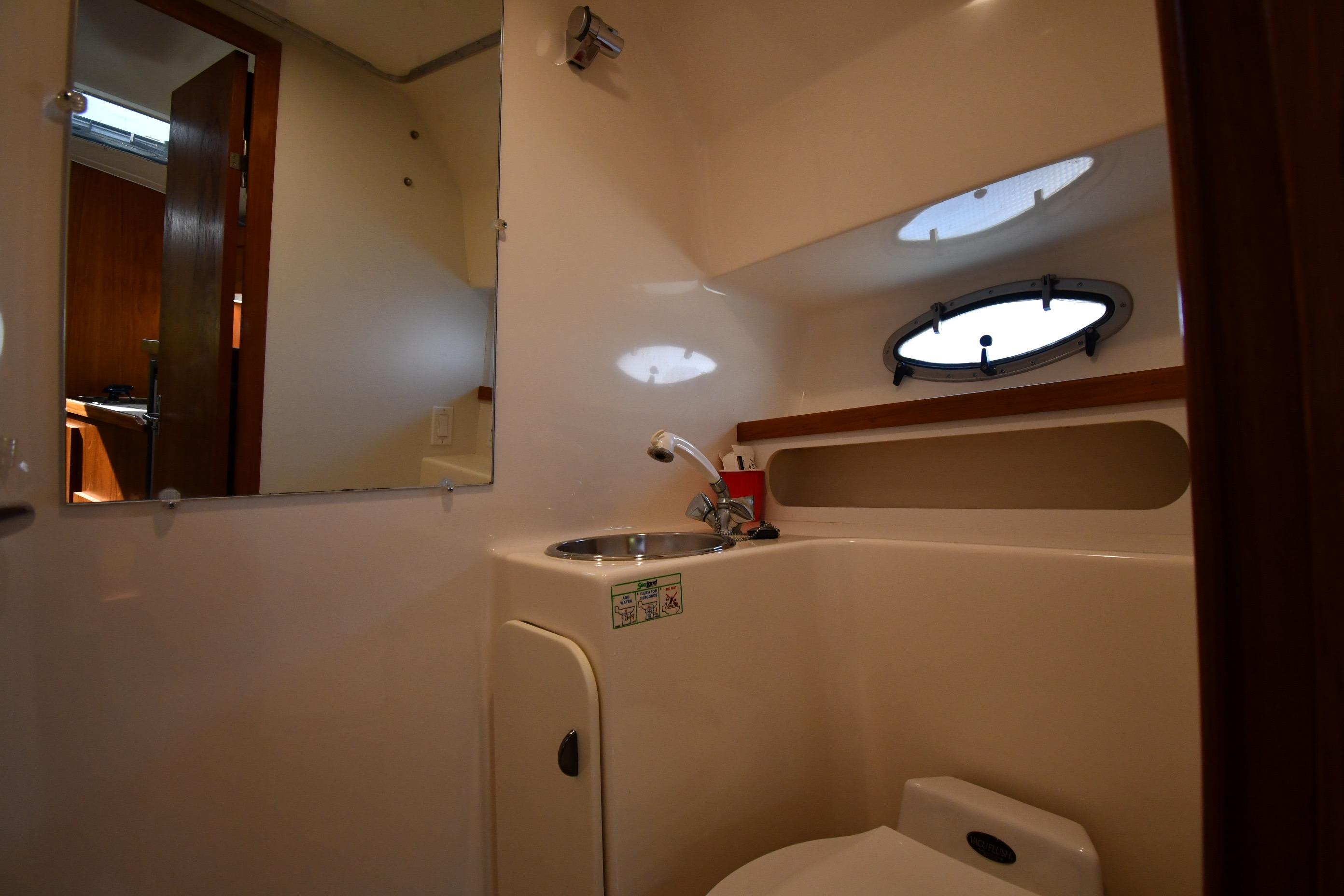 Bathroom interior of 1998 Tiara Yachts 3100 Open, featuring sink and porthole window.