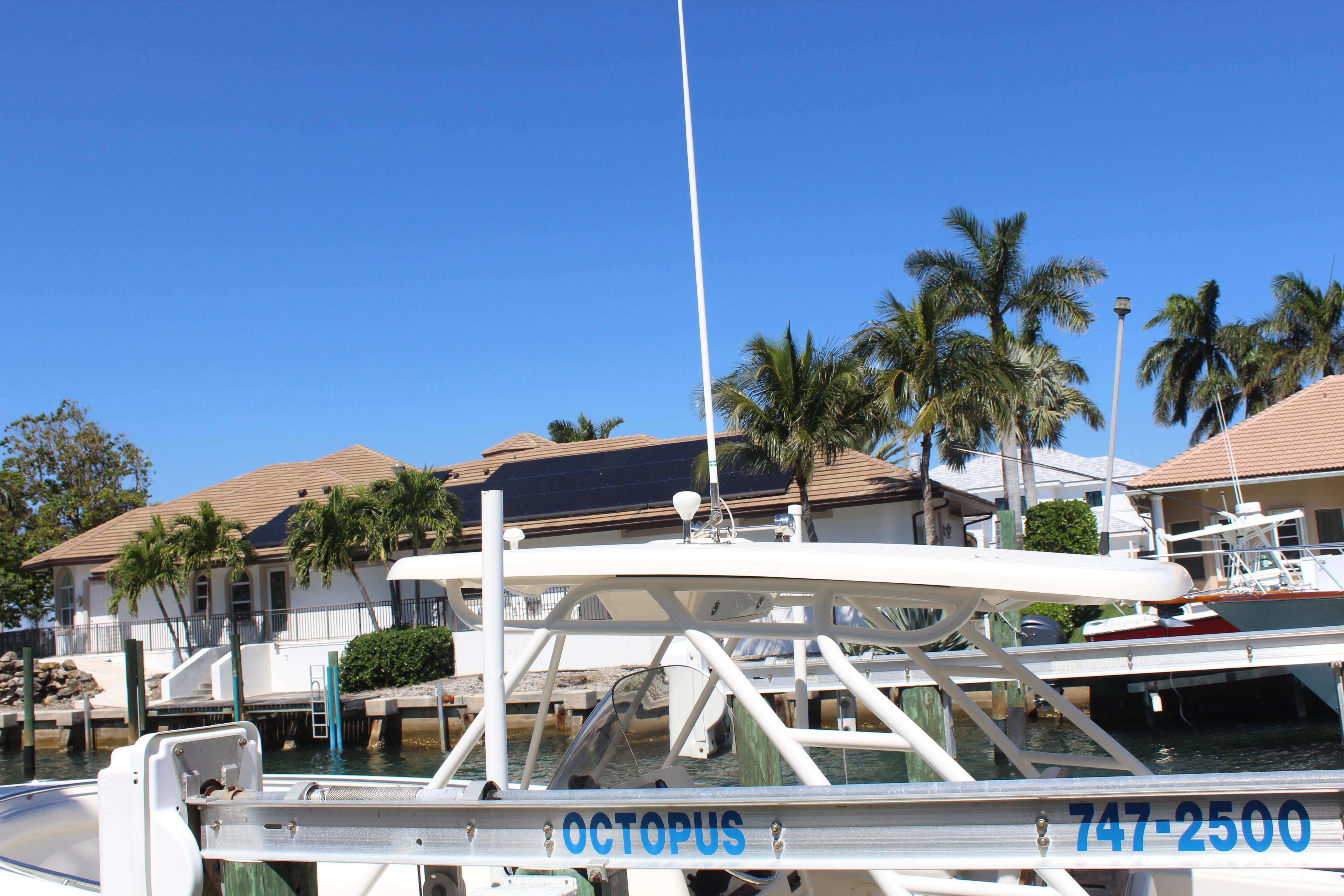 2008 Pursuit S 310 Sport boat docked near waterfront homes and palm trees.