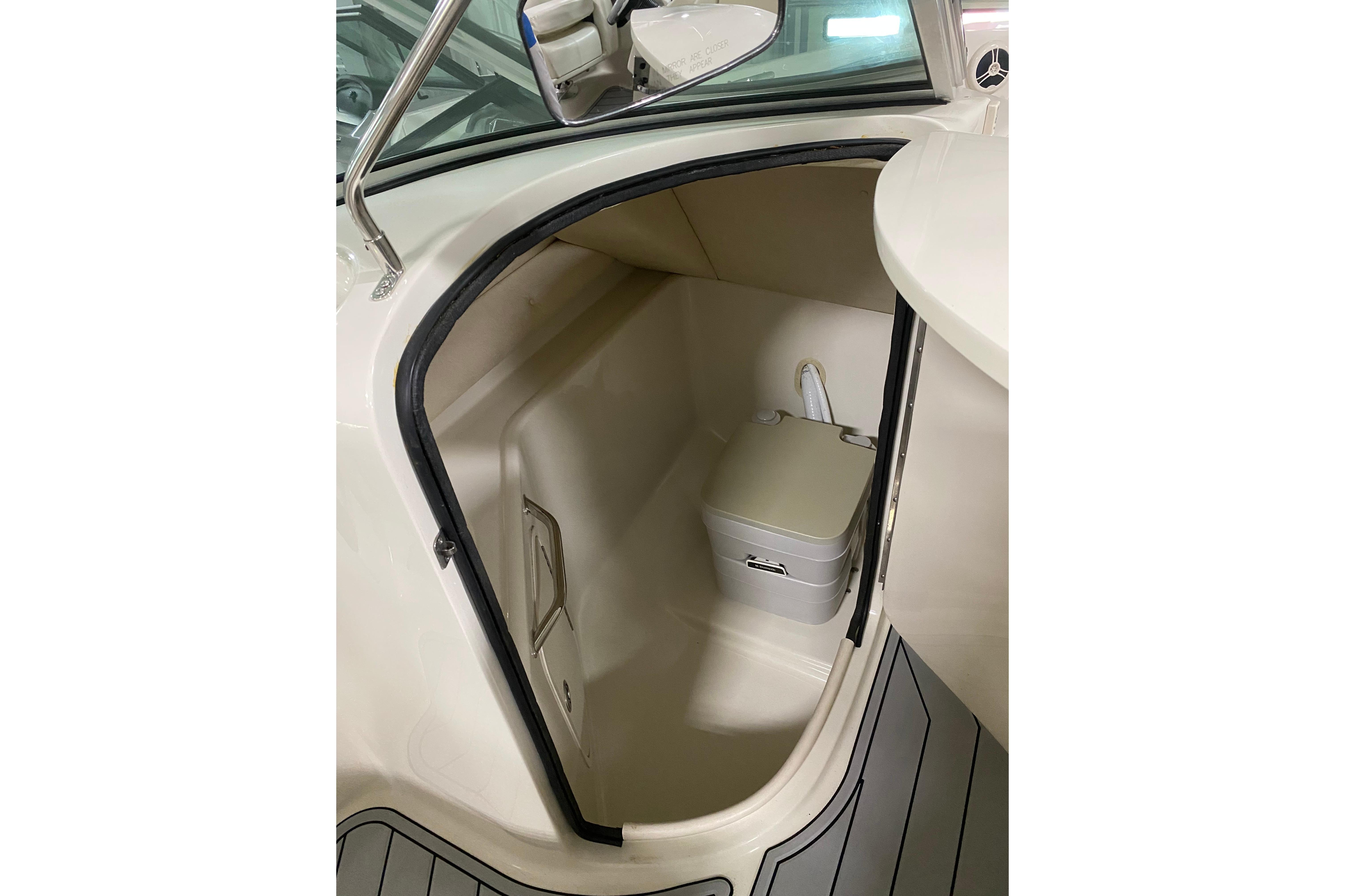 2008 Sea Ray 240 Sundeck interior with compact marine toilet and storage space.