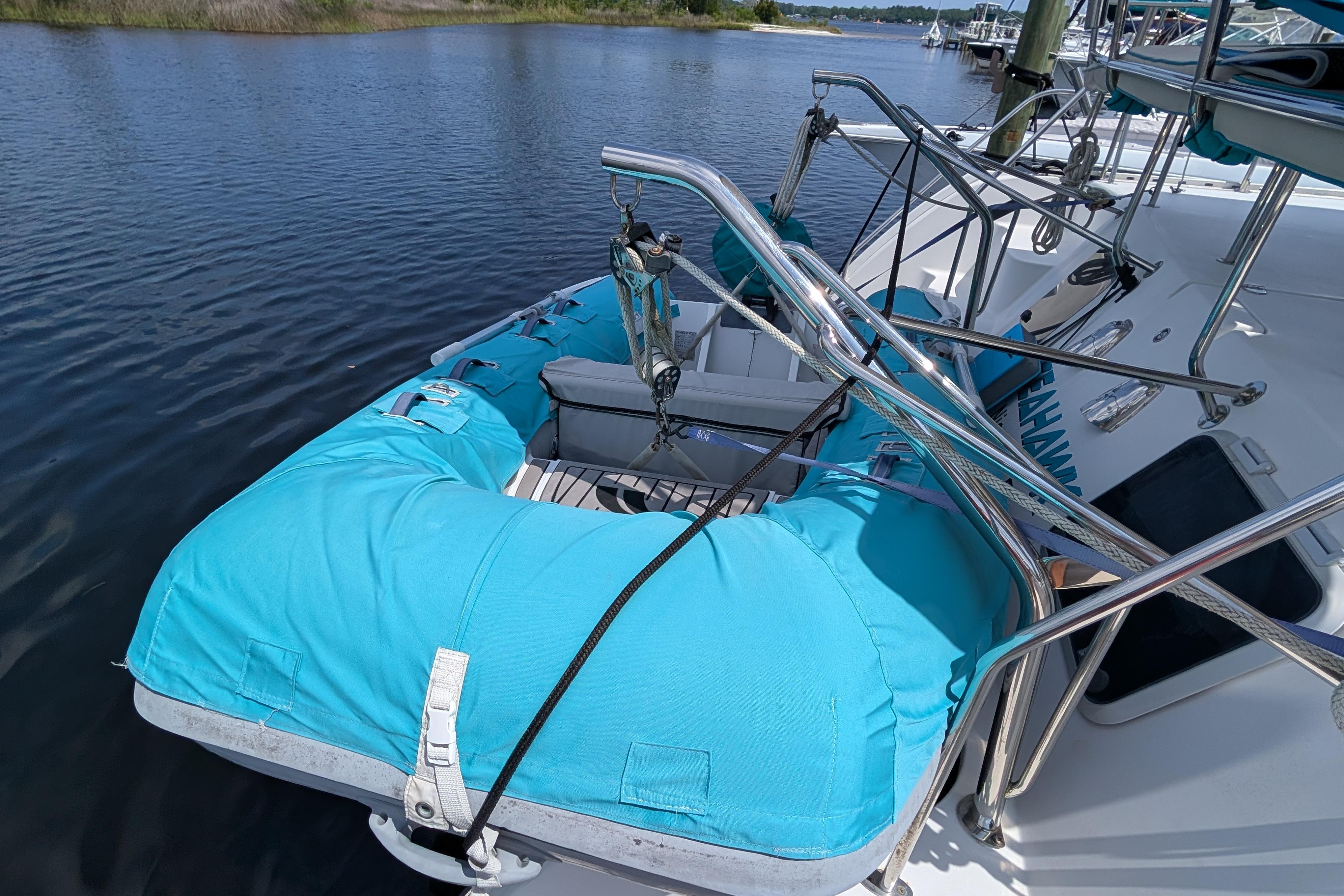 2004 PDQ 34 Powercat with blue dinghy on calm water.