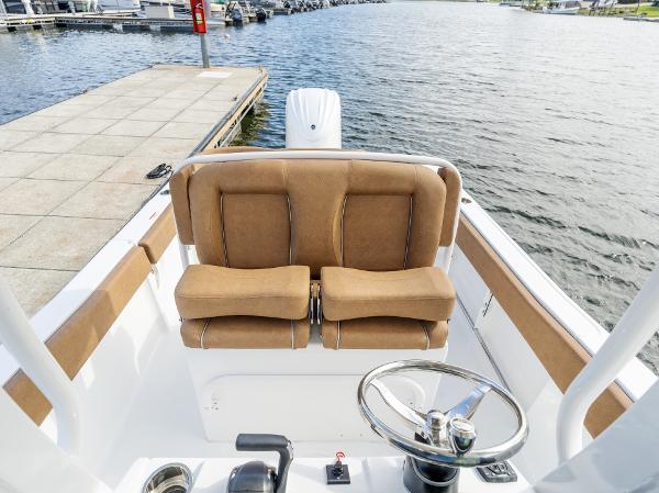 2025 Sea Hunt Ultra 235 SE boat interior with tan seating and steering wheel by the dock.