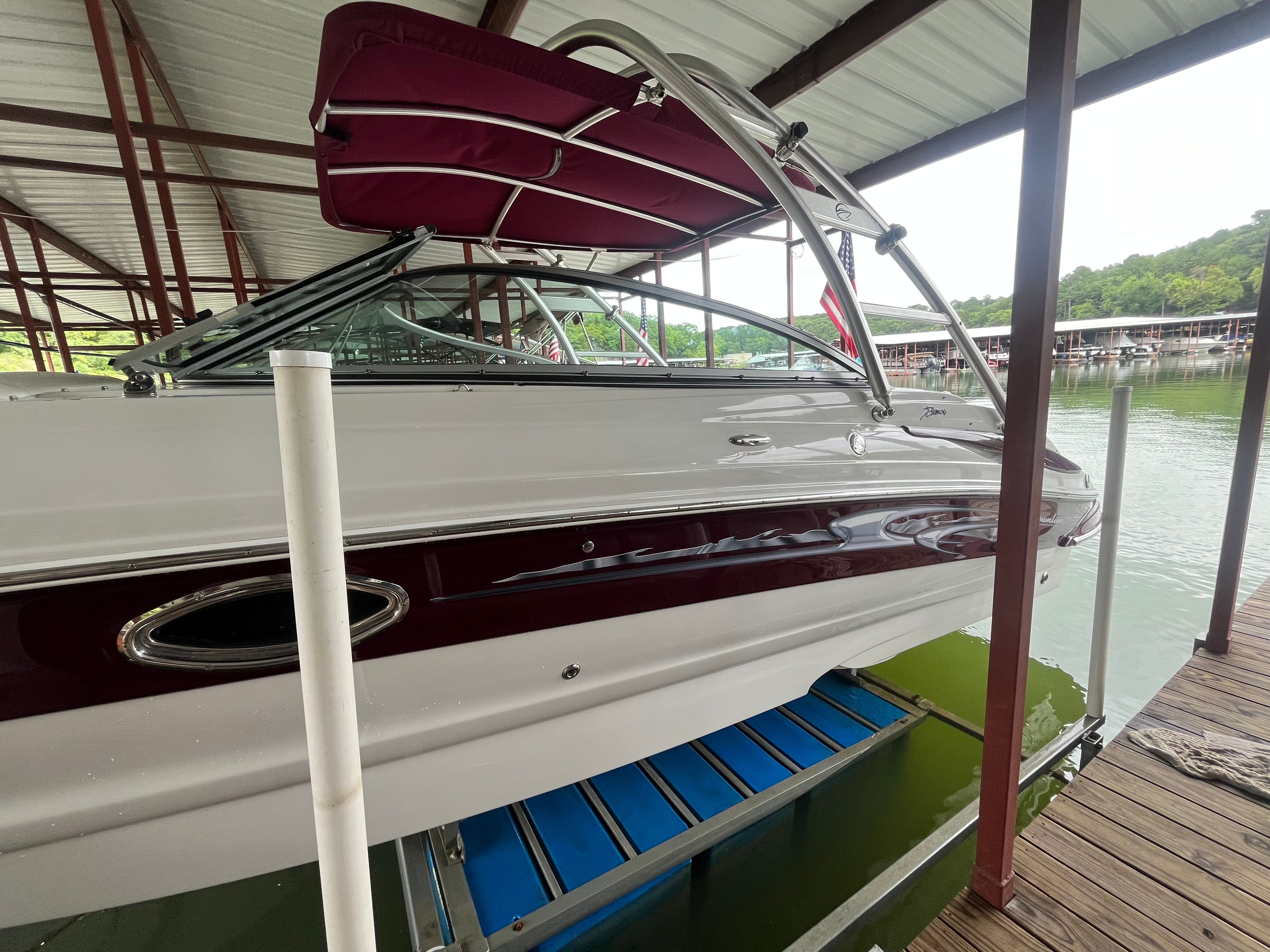 A 2008 Crownline 252EX boat is docked under a covered area by the water.