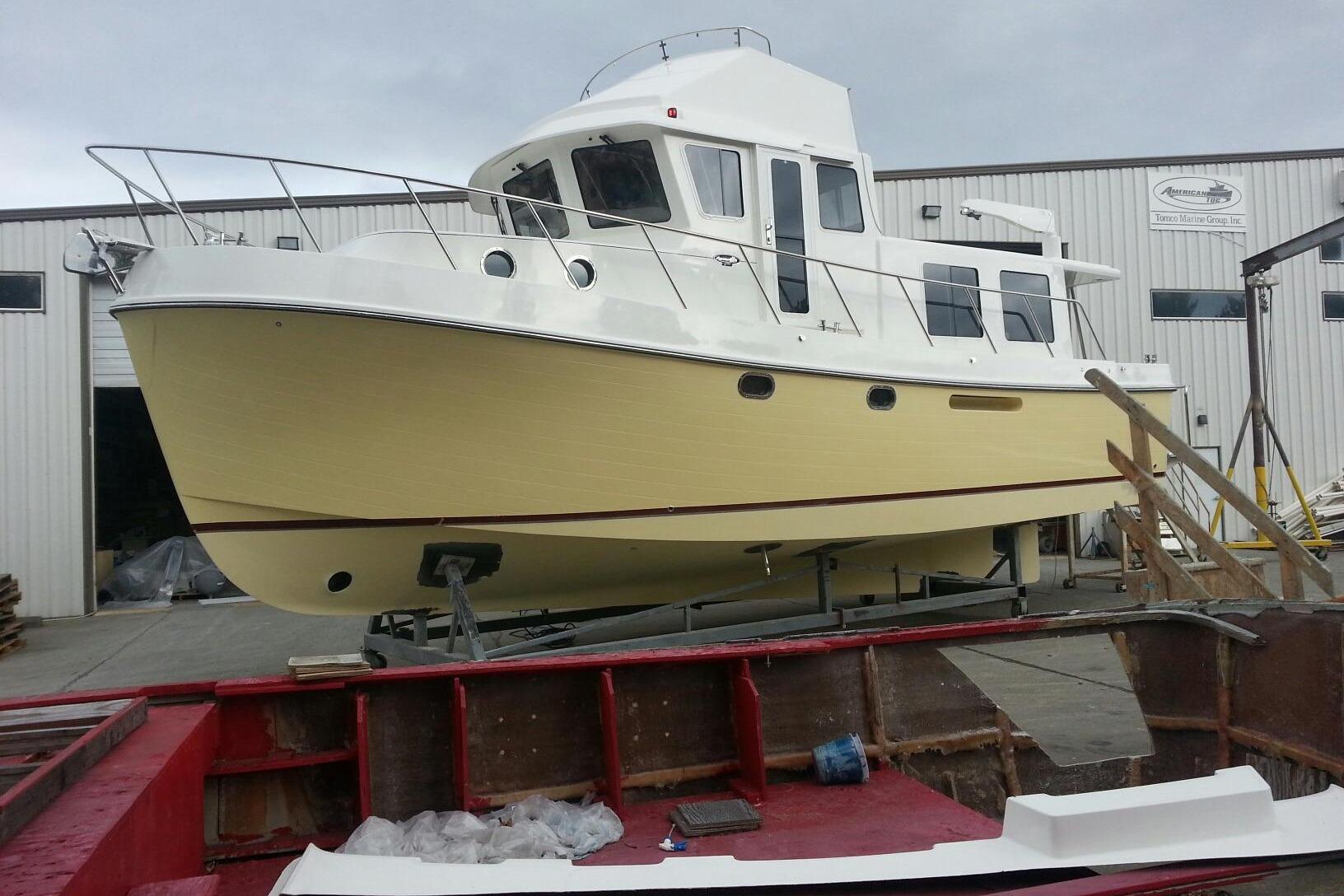 2015 American Tug 435 boat in a shipyard, showcasing its yellow hull and white cabin.