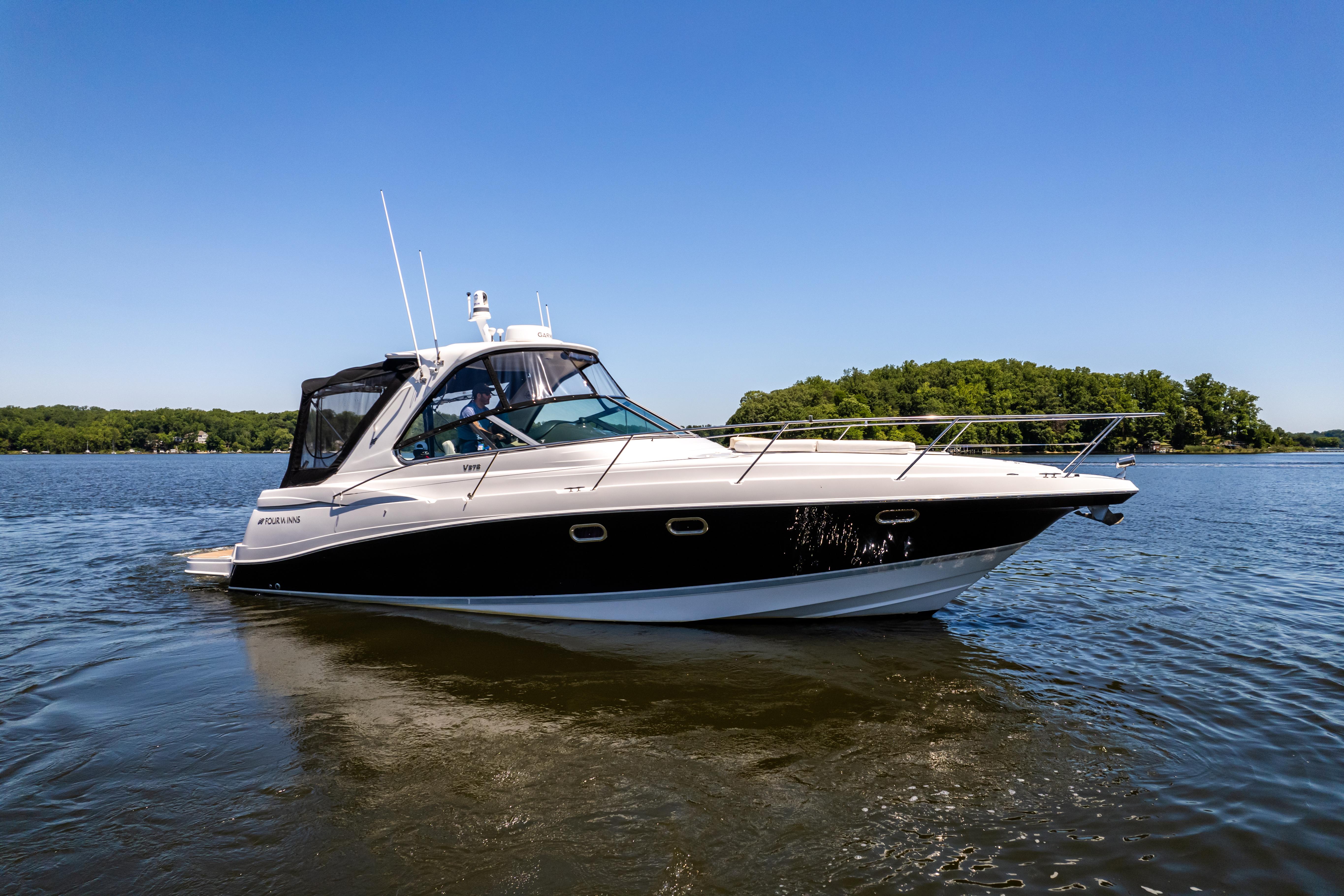2008 Four Winns V378 boat cruising on a calm lake under a clear blue sky.
