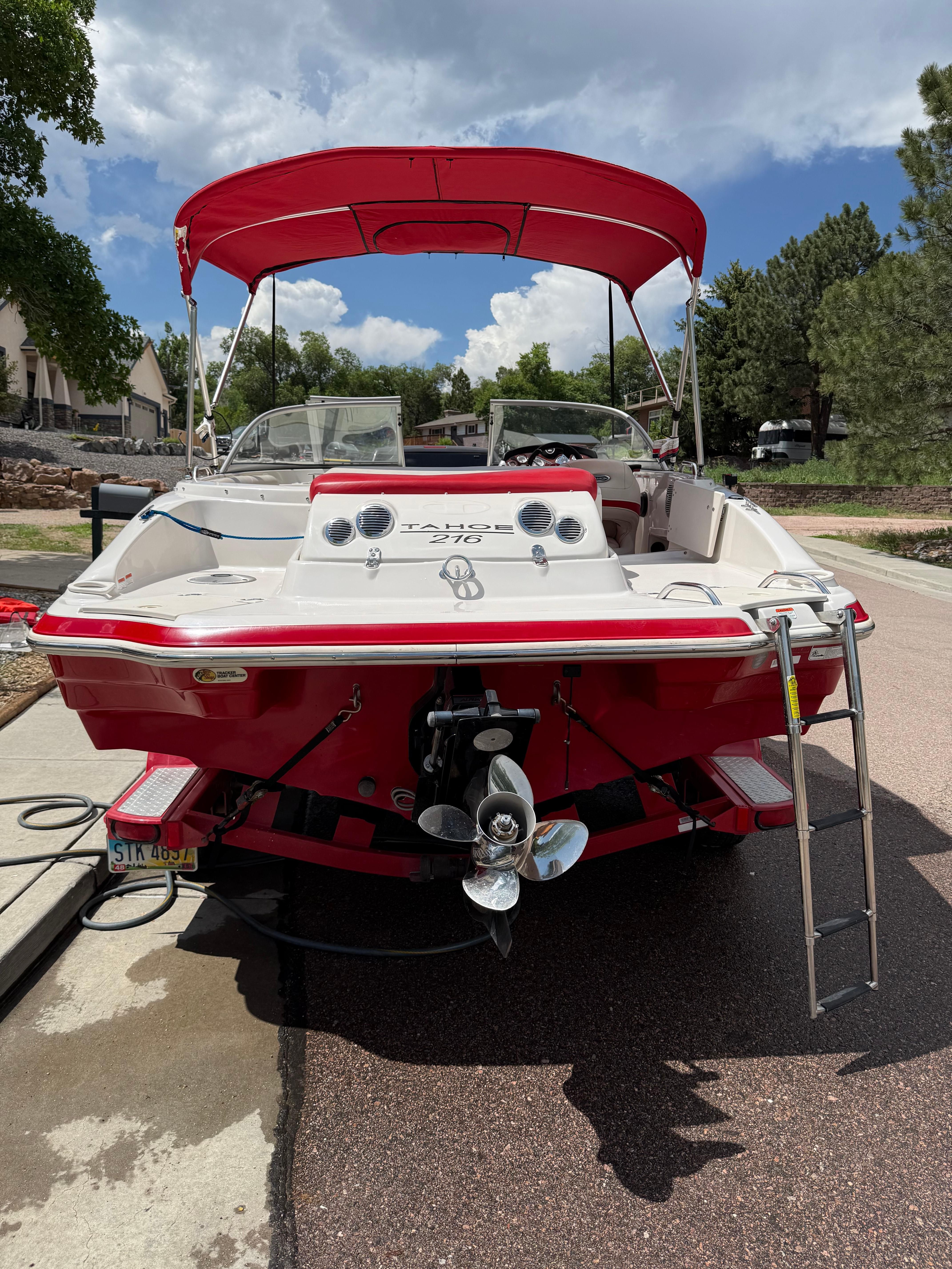 Red 2011 Tahoe 216 WT boat parked on pavement.