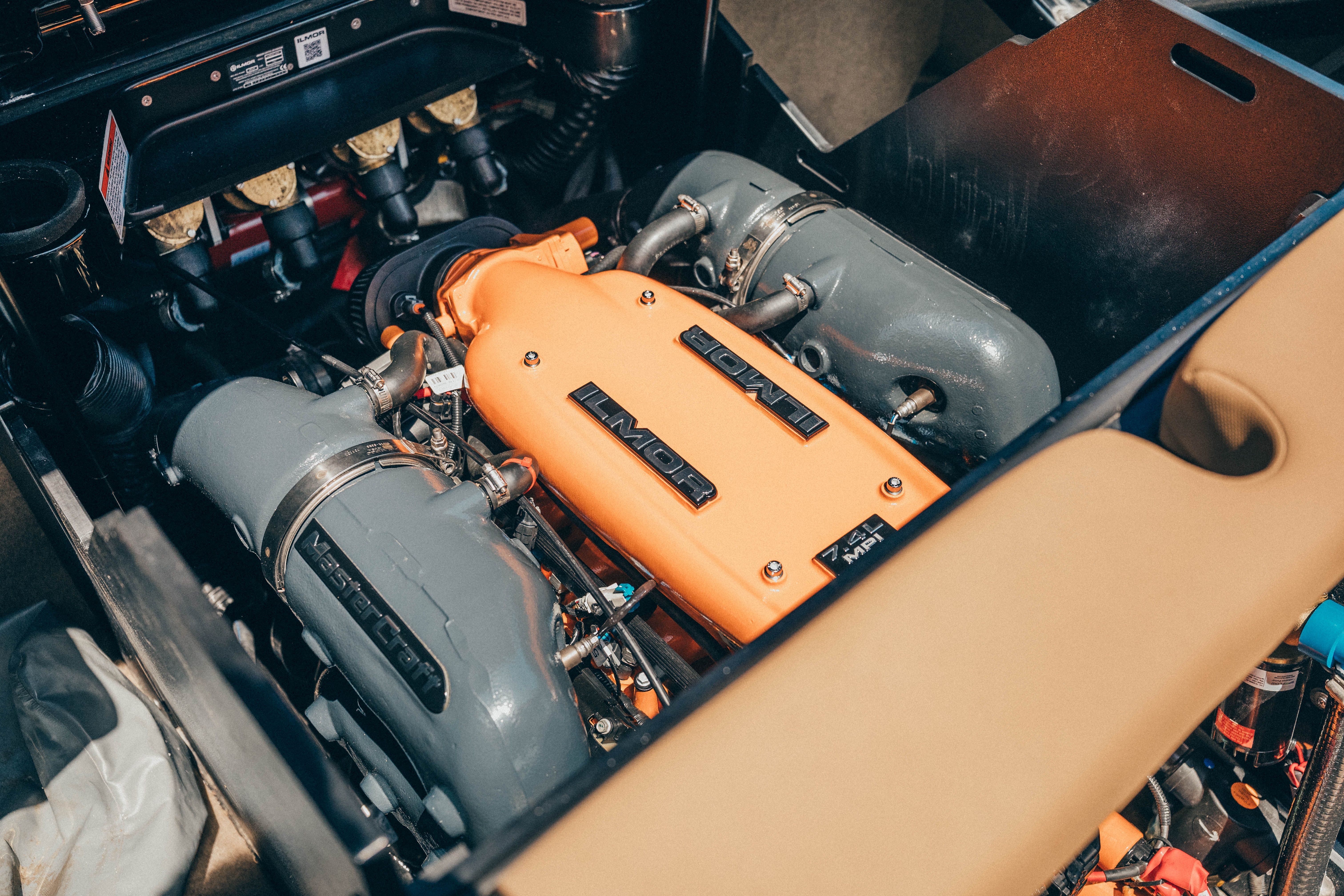 The engine compartment of a 2021 MasterCraft X26 features a powerful engine with an orange casing.