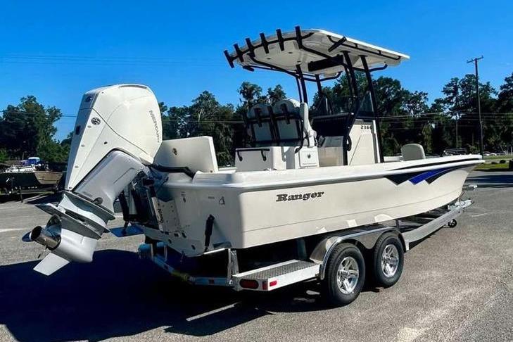 2026 Ranger 2360 Bay boat on trailer, featuring outboard motor and T-top, parked outdoors.