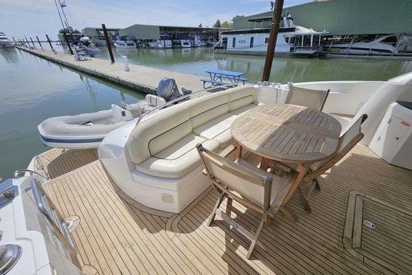 Luxurious Sunseeker Manhattan 66 yacht deck with seating and table, docked at marina.